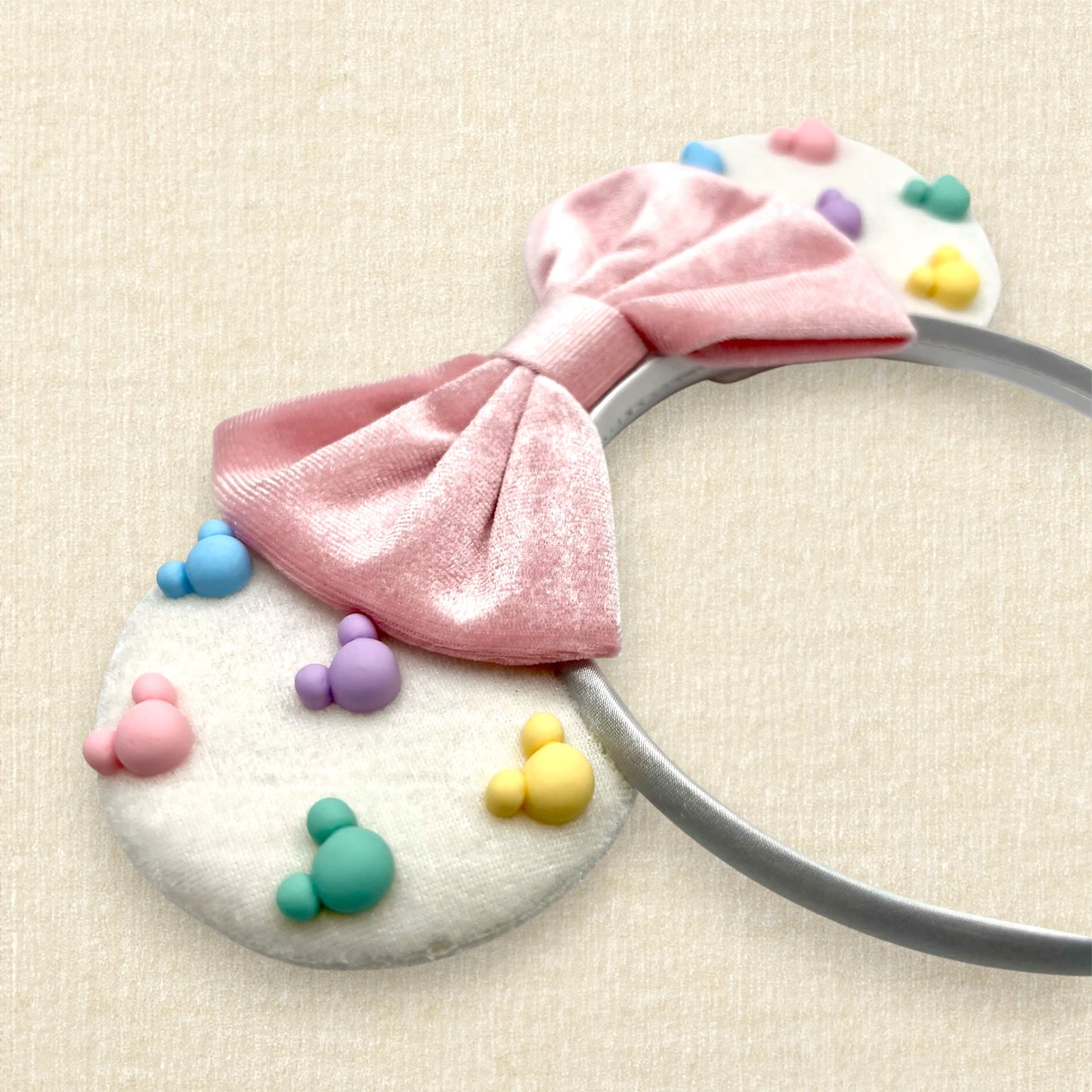 White velvet mouse ears with colorful Mickey pearls and pink velvet bow