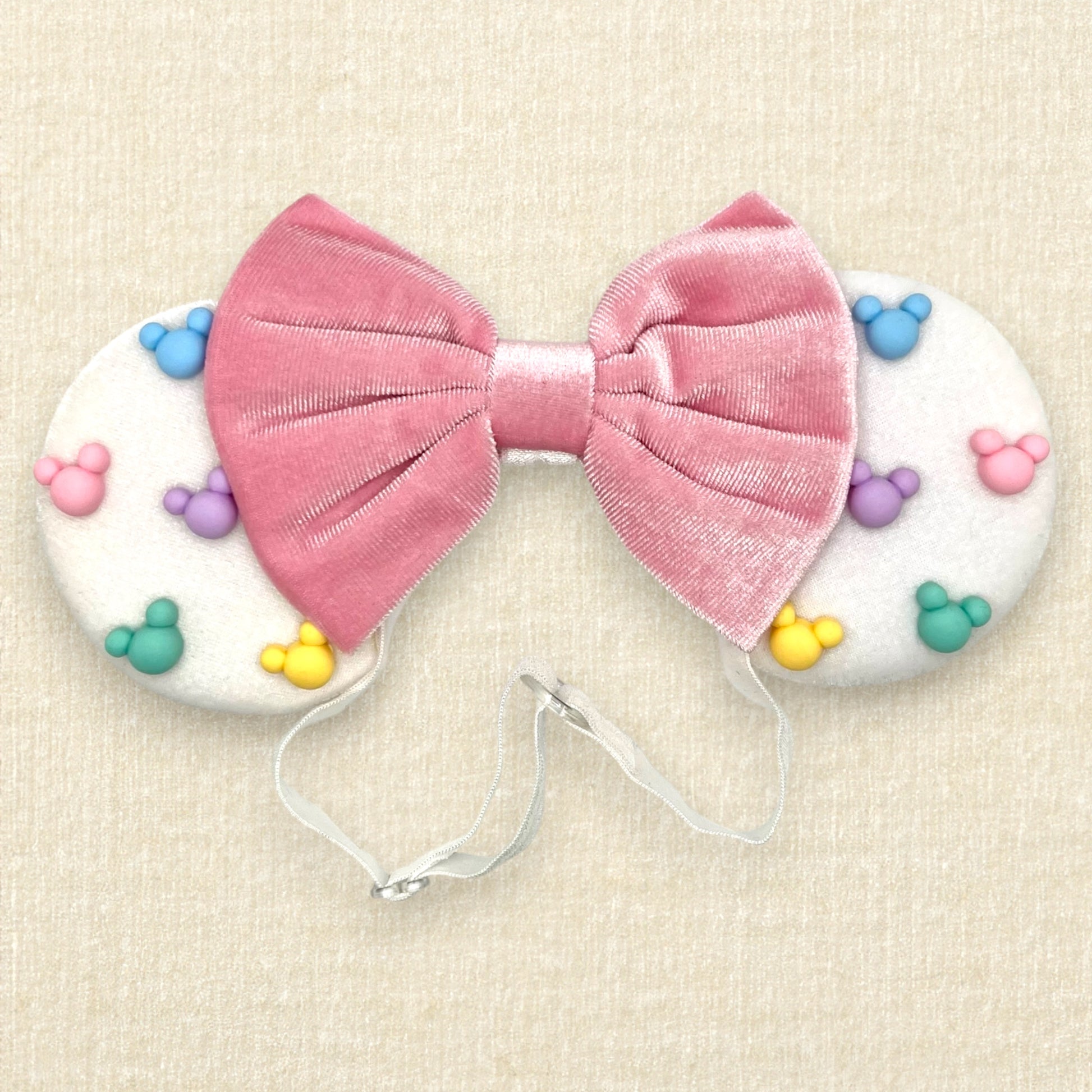 White velvet mouse ears with colorful pastel mouse pearls and pastel pink velvet bow on an elastic headband