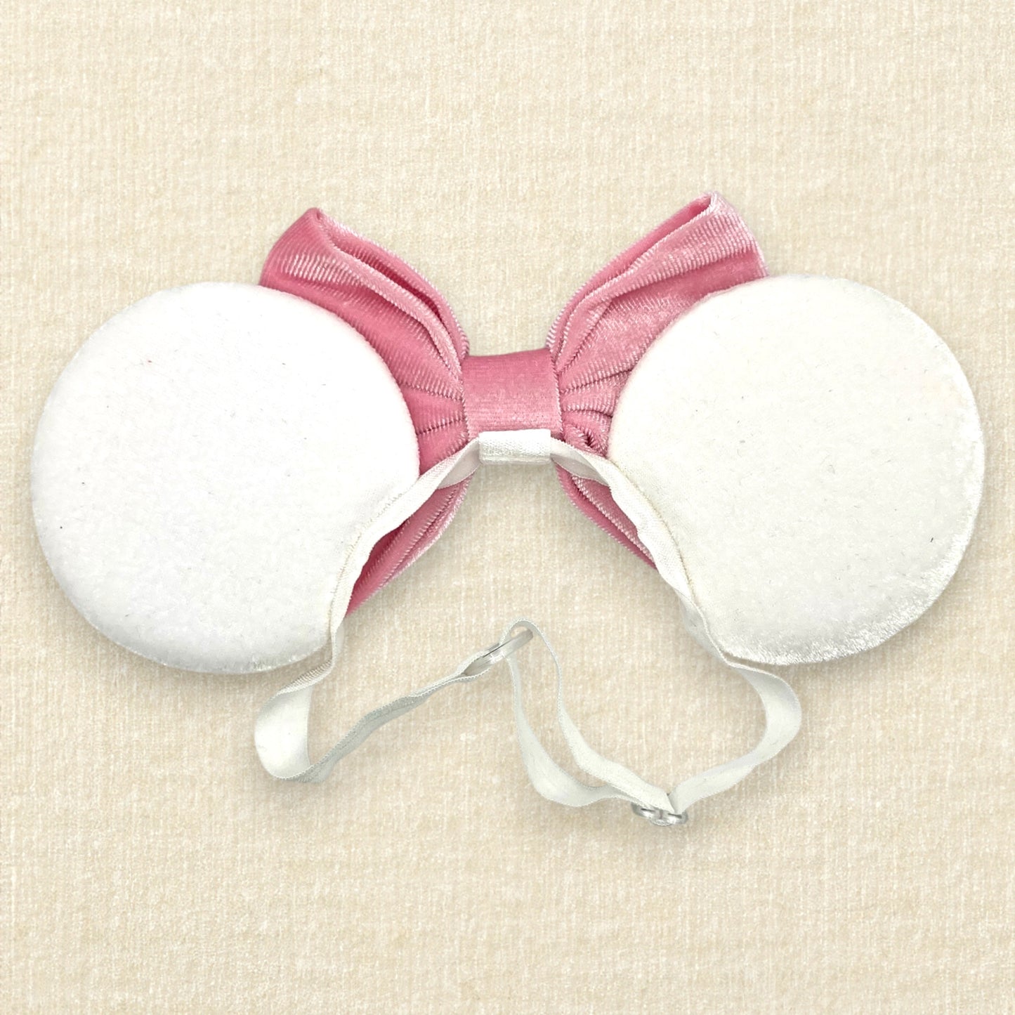 White velvet mouse ears with colorful pastel mouse pearls and pastel pink velvet bow on an elastic headband (back view)