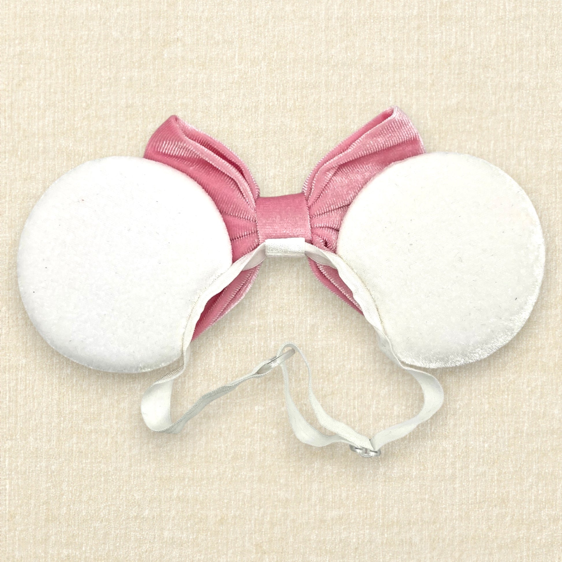 White velvet mouse ears with colorful pastel mouse pearls and pastel pink velvet bow on an elastic headband (back view)