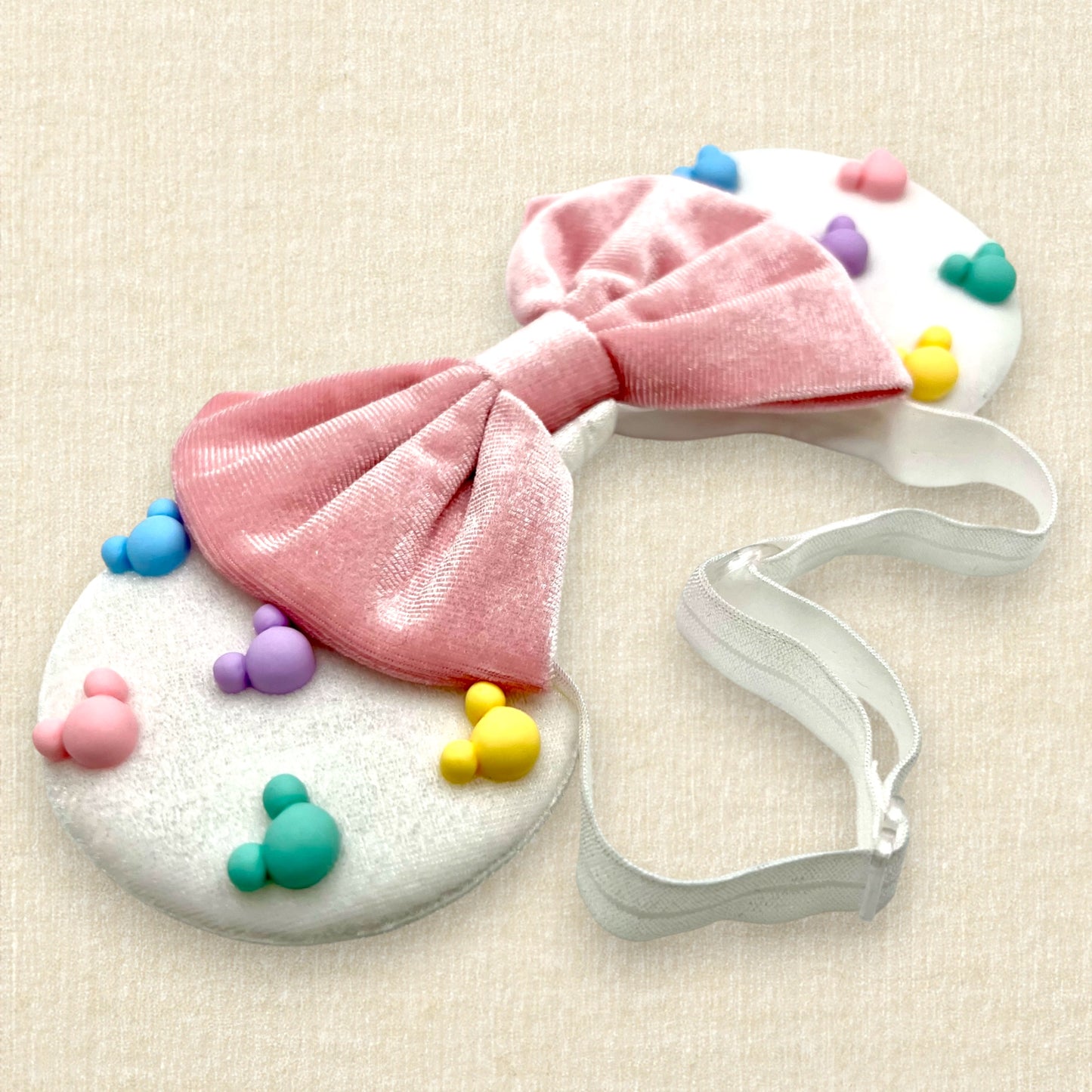 White velvet mouse ears with colorful pastel mouse pearls and pastel pink velvet bow on an elastic headband