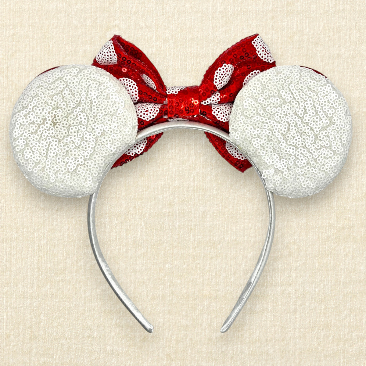 A Christmas mouse ears headband with white sequin ears, red glitter swirls, and a red sequin bow with white polka dots. (Back view)