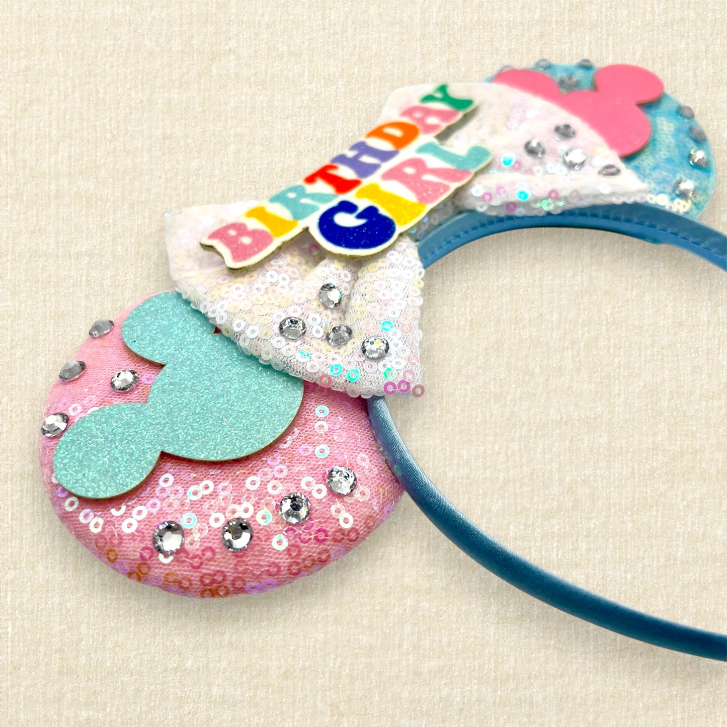Pink and blue mouse ears with mouse silhouettes, white sequin bow, and colorful "Birthday Girl" text
