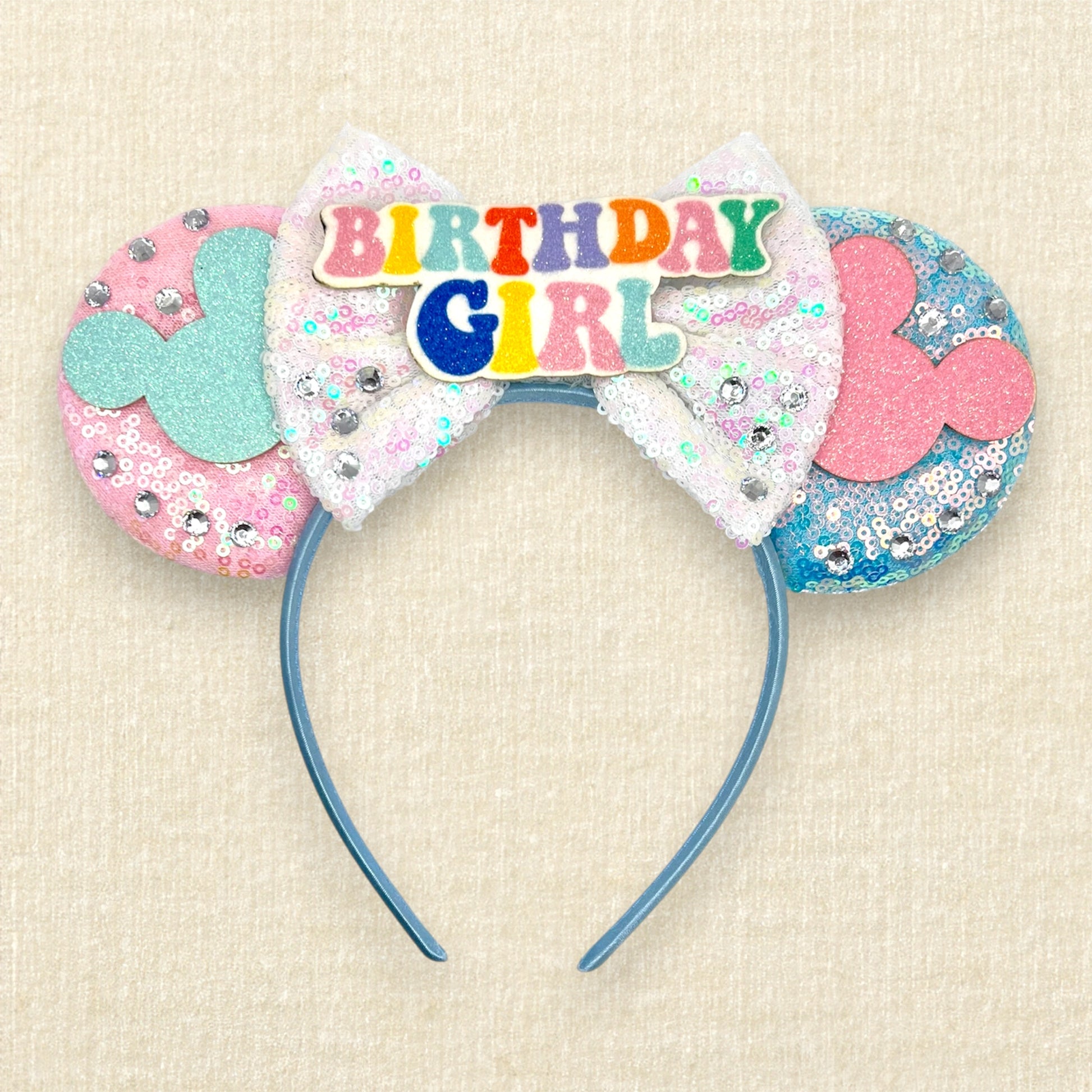 Pink and blue mouse ears with mouse silhouettes, white sequin bow, and colorful "Birthday Girl" text