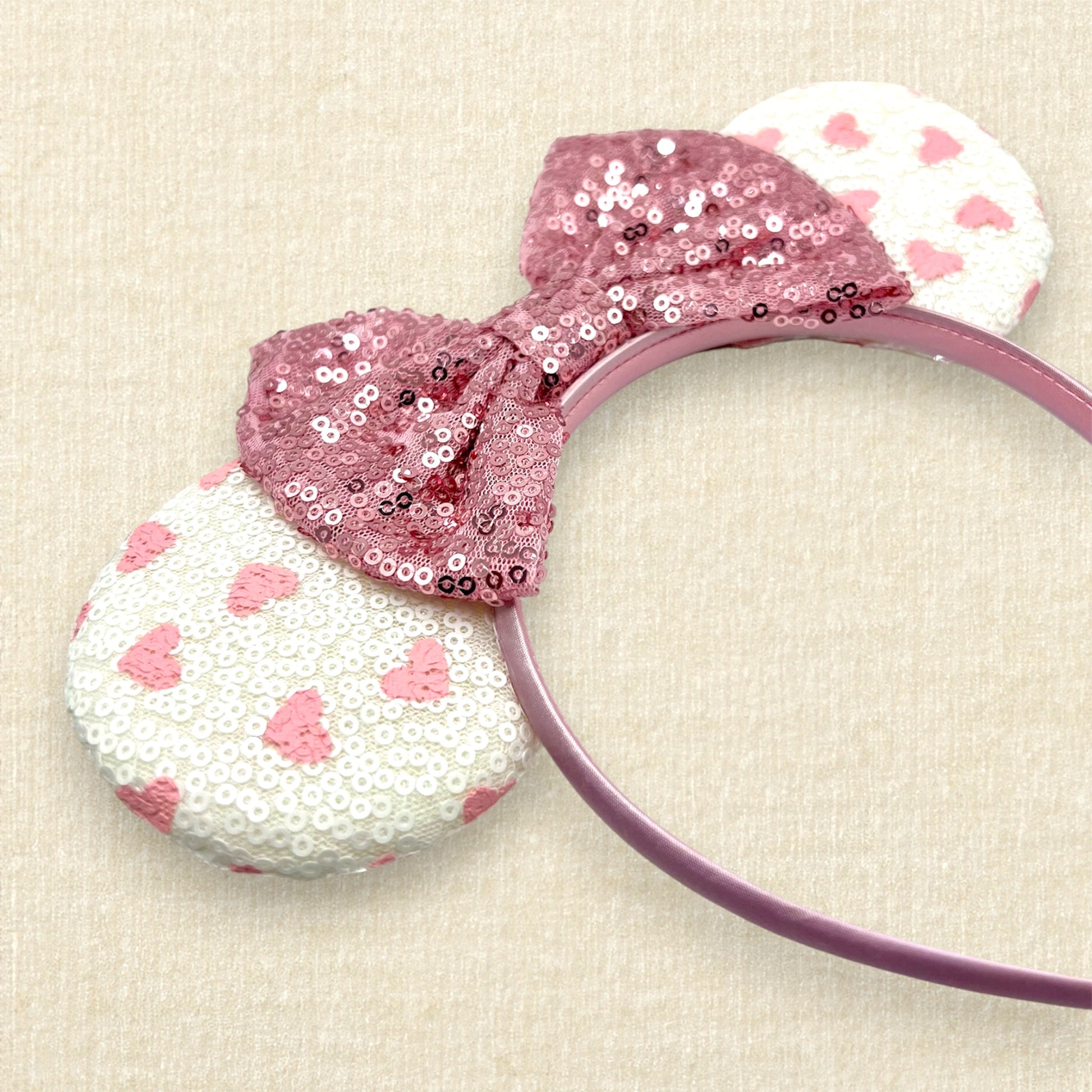 White sequin mouse ears with small pink hearts and rose gold sequin bow