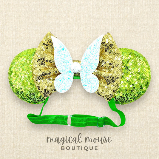 Green sequin mouse ears headband with gold bow and glitter fairy wings, on a beige background with "Magical Mouse Boutique" branding