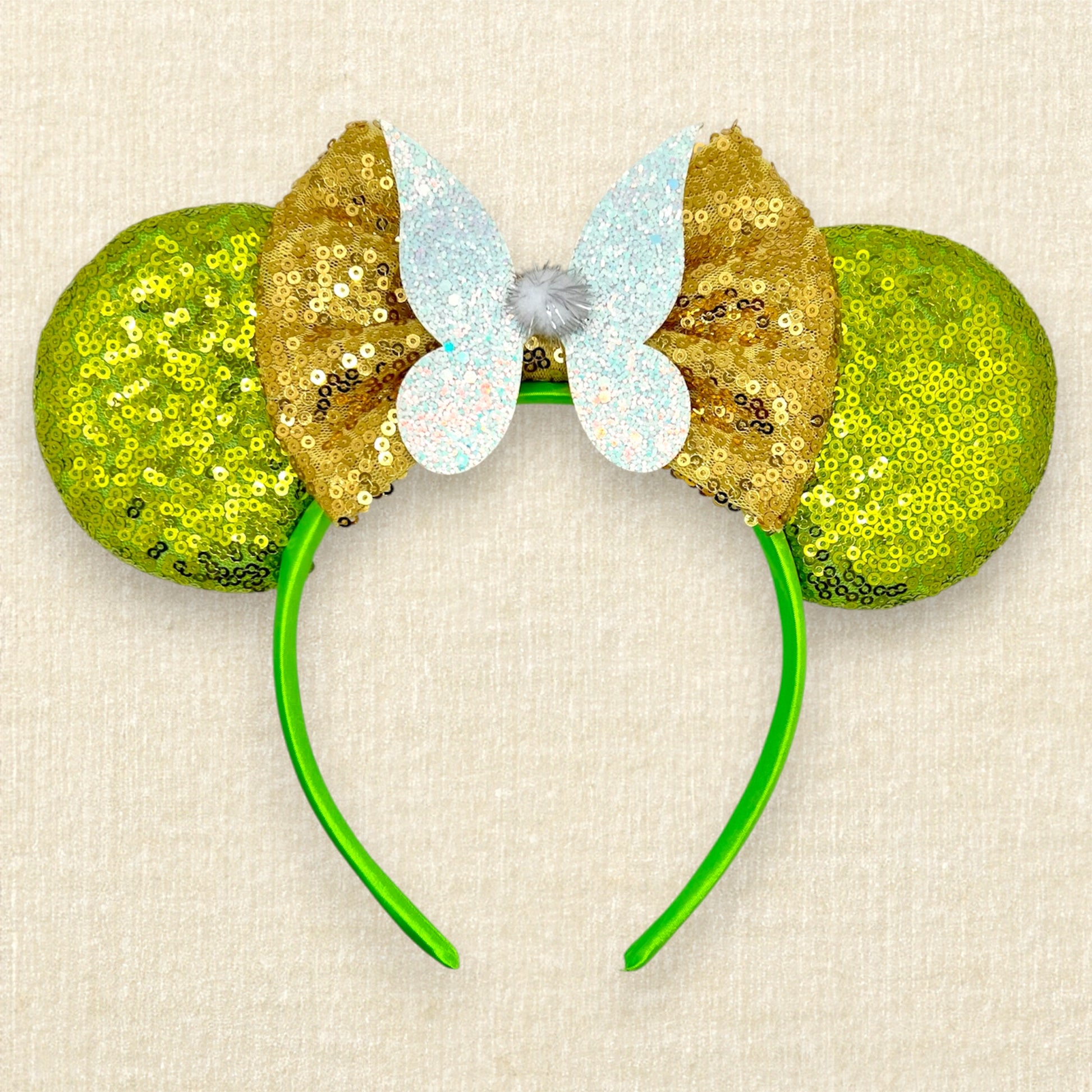 Light green sequin mouse ears headband with gold bow, glitter fairy wings, and pom-pom centerpiece