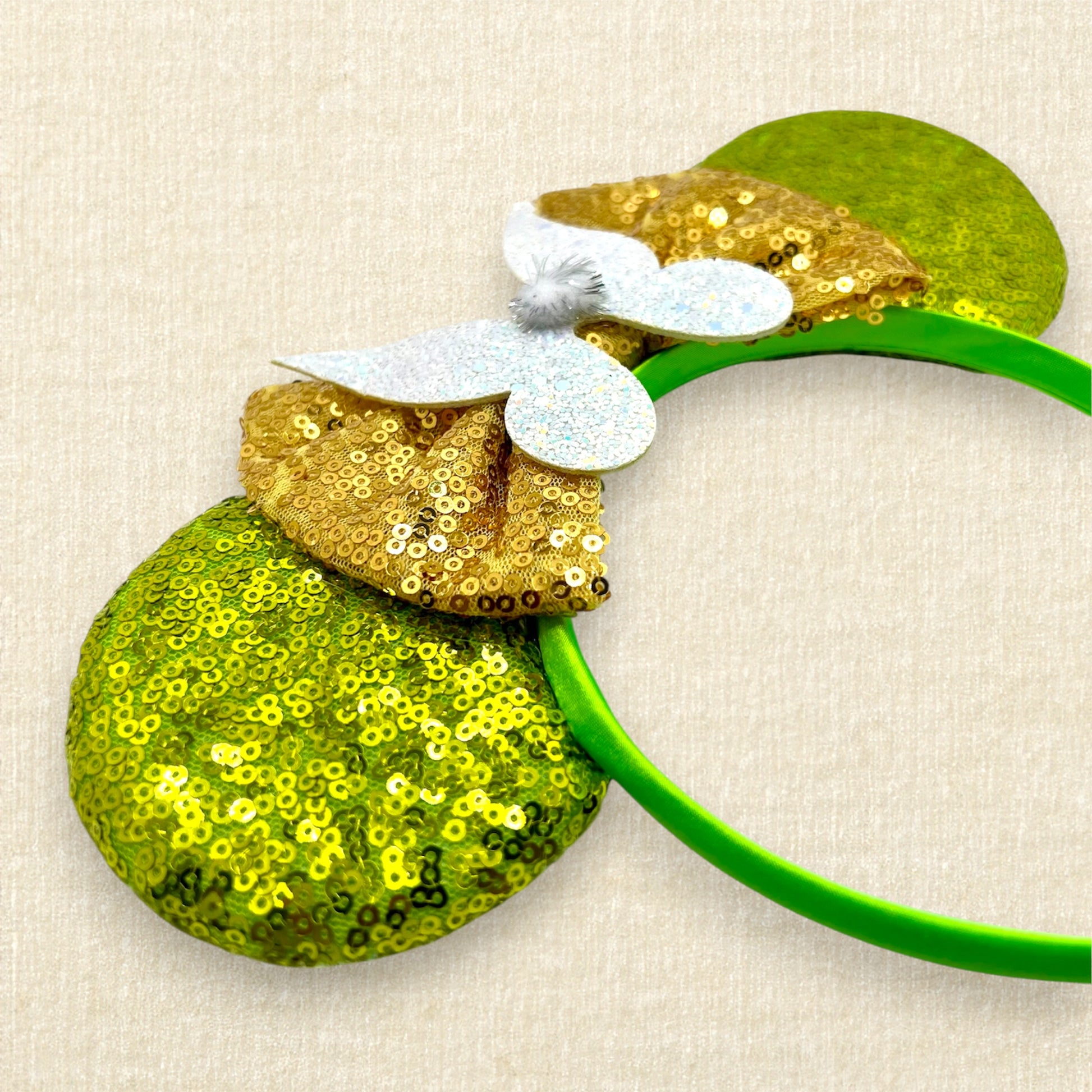 Light green sequin mouse ears headband with gold bow, glitter fairy wings, and pom-pom centerpiece