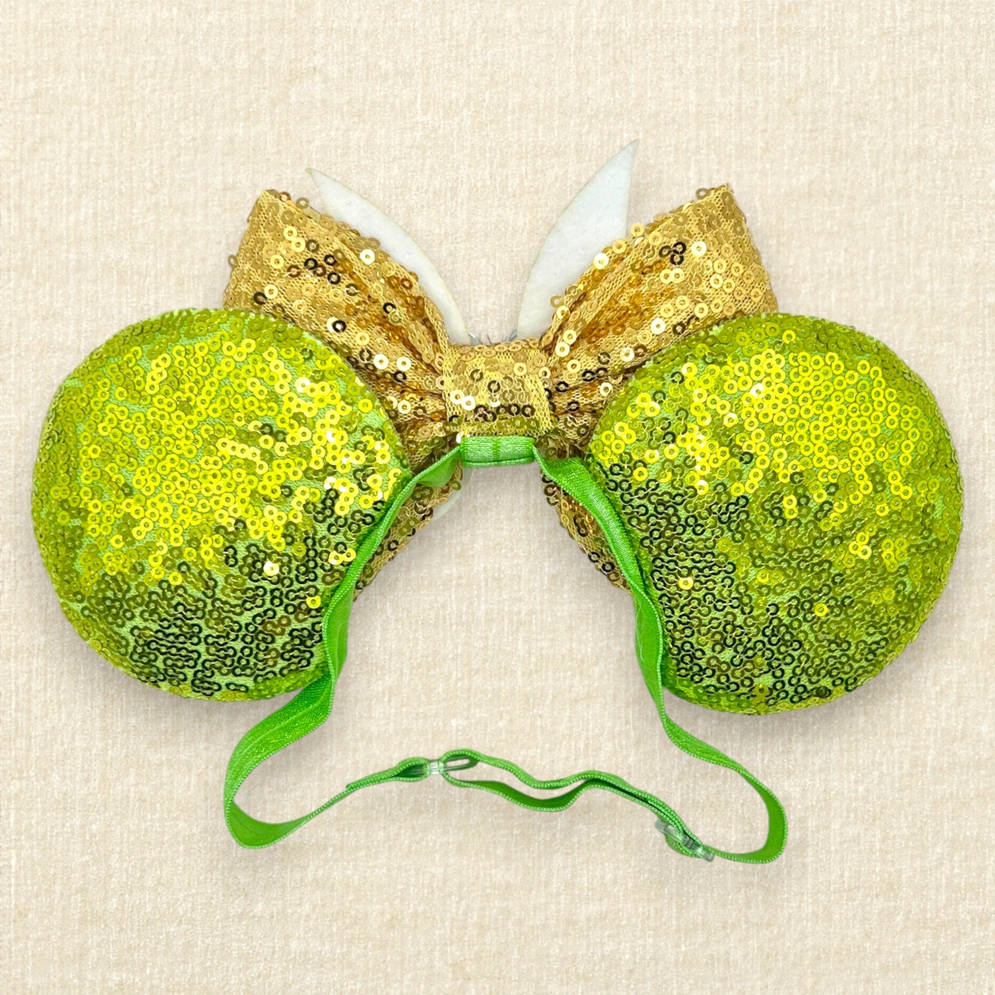 Light green sequin mouse ears with gold sequin bow and glitter fairy wings on an elastic headband (back view)