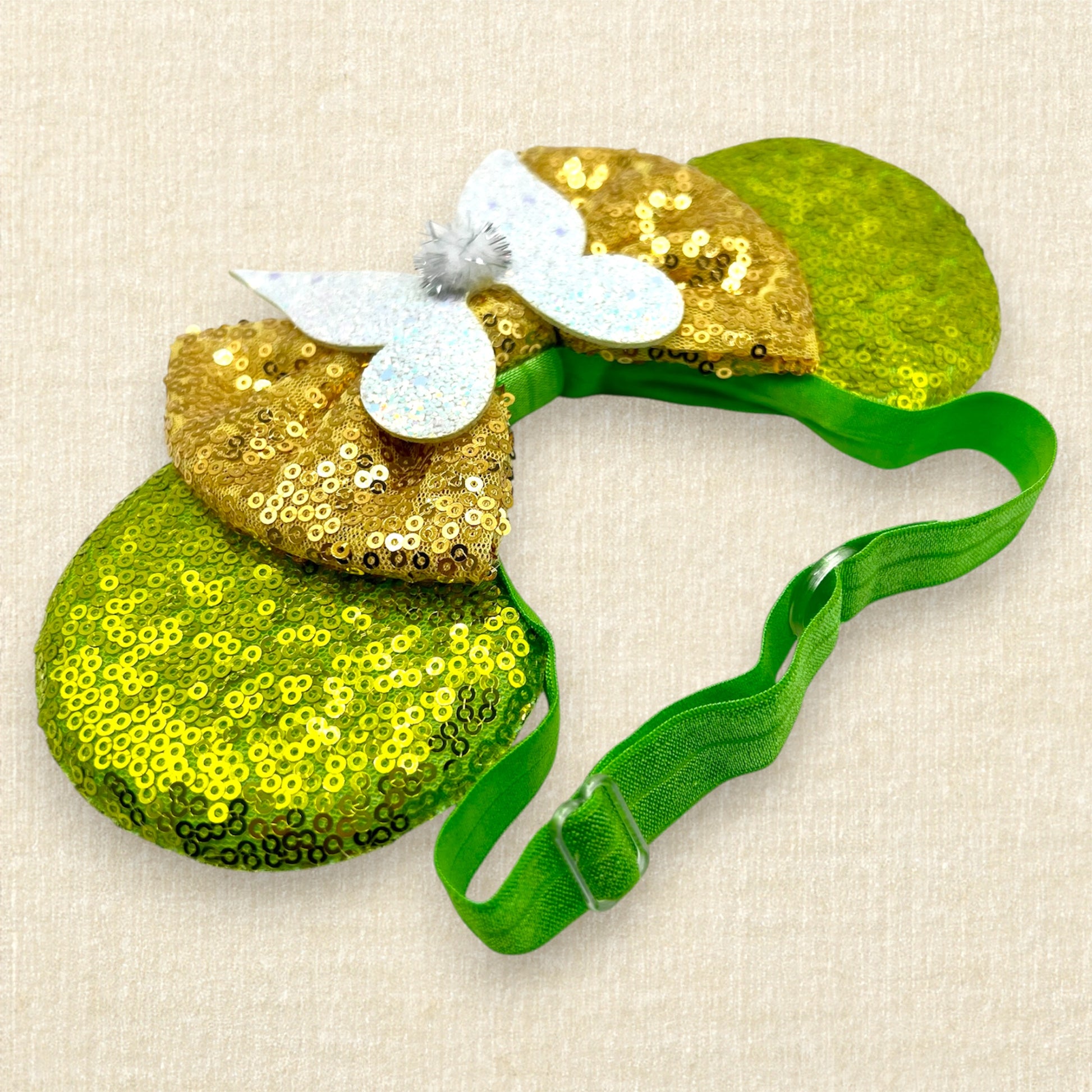 Light green sequin mouse ears with gold sequin bow and glitter fairy wings on an elastic headband