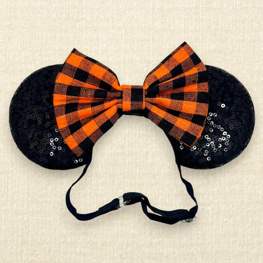 Fall-themed mouse ears with black ears and orange and black buffalo plaid bow on an elastic headband