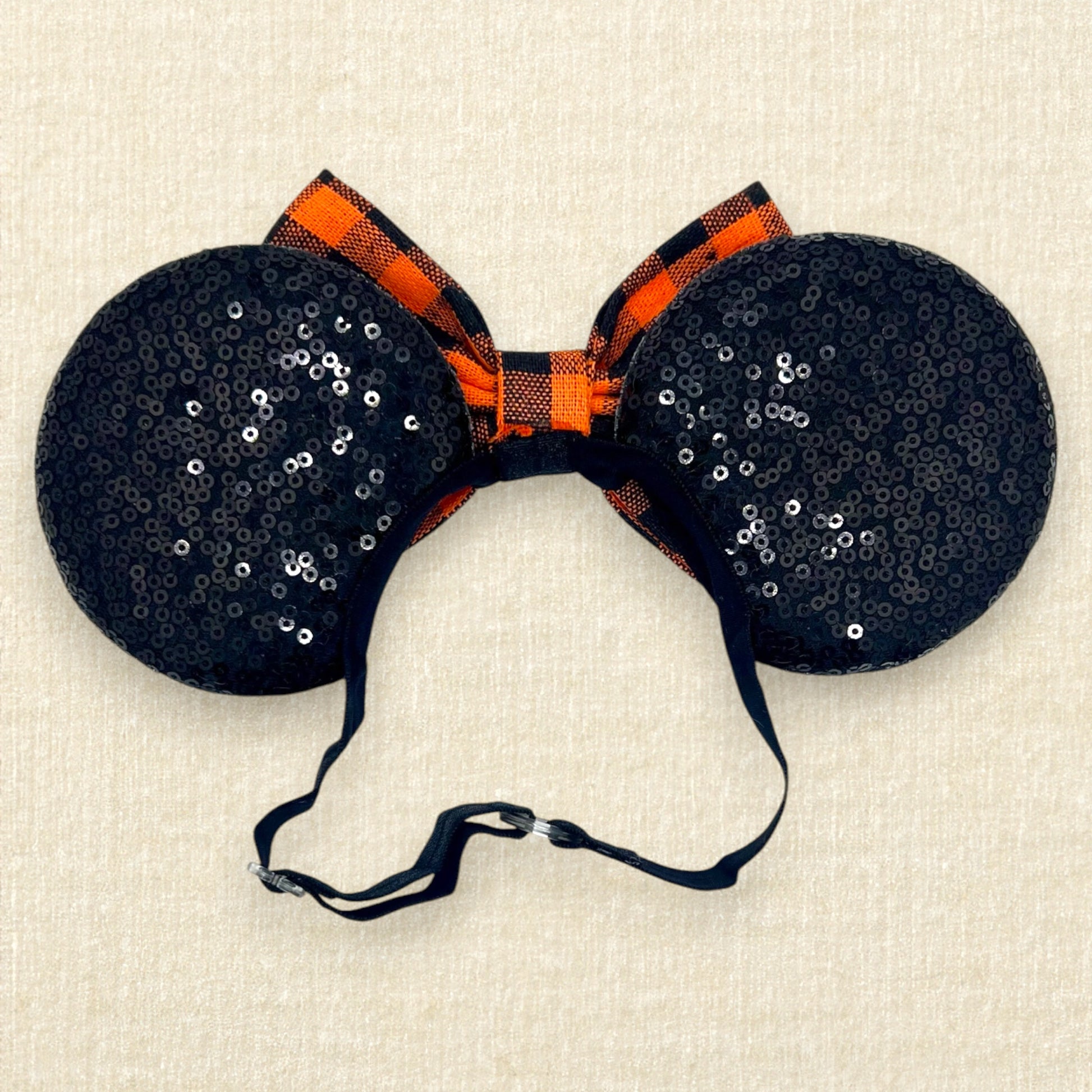 Fall-themed mouse ears with black ears and orange and black buffalo plaid bow on an elastic headband (back view)