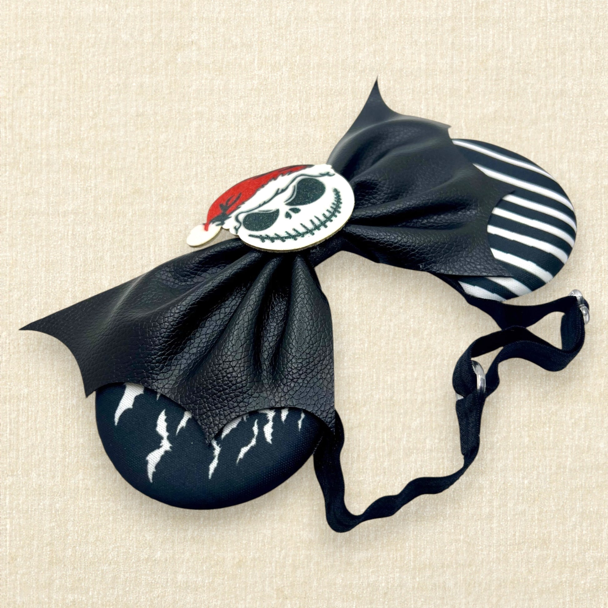 Halloween-themed mouse ears with black and white fabric ears, black faux leather bat wing bow, and glitter Sandy Claws centerpiece on an elastic headband