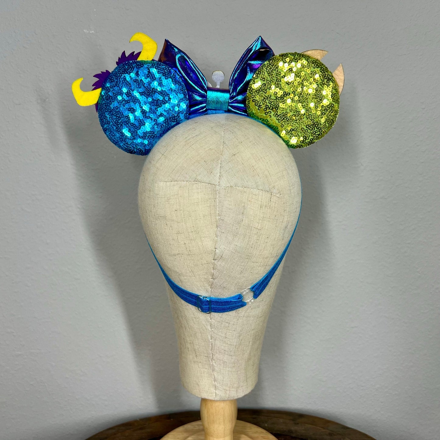 Colorful monster-themed elastic mouse ears headband on a mannequin