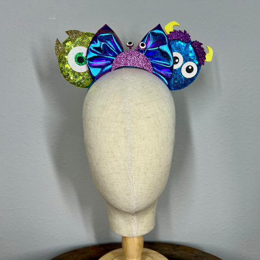 Colorful monster-themed elastic mouse ears headband on a mannequin