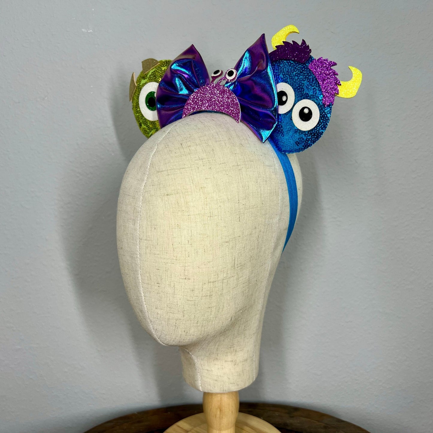 Colorful monster-themed elastic mouse ears headband on a mannequin