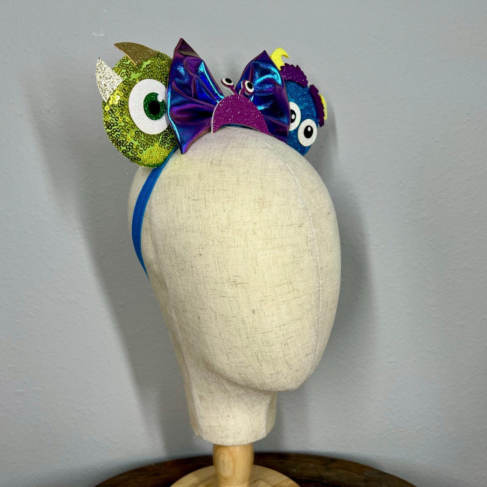 Colorful monster-themed elastic mouse ears headband on a mannequin
