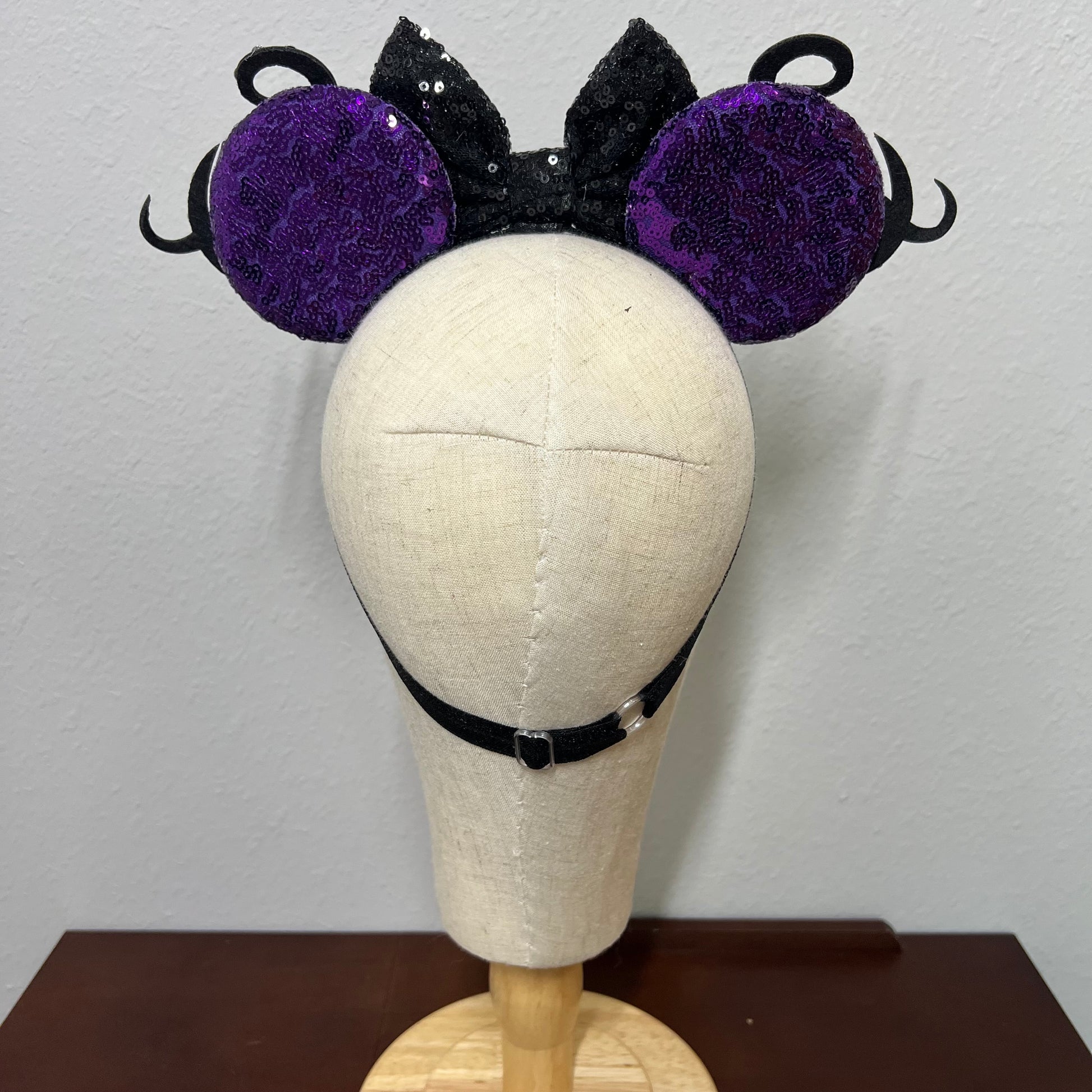 Black and purple mouse ears headband on a mannequin head against a plain background