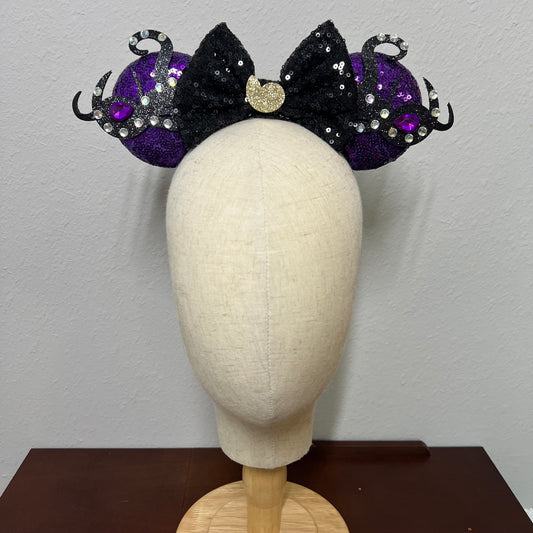 Black and purple mouse ears headband on a mannequin head against a plain background