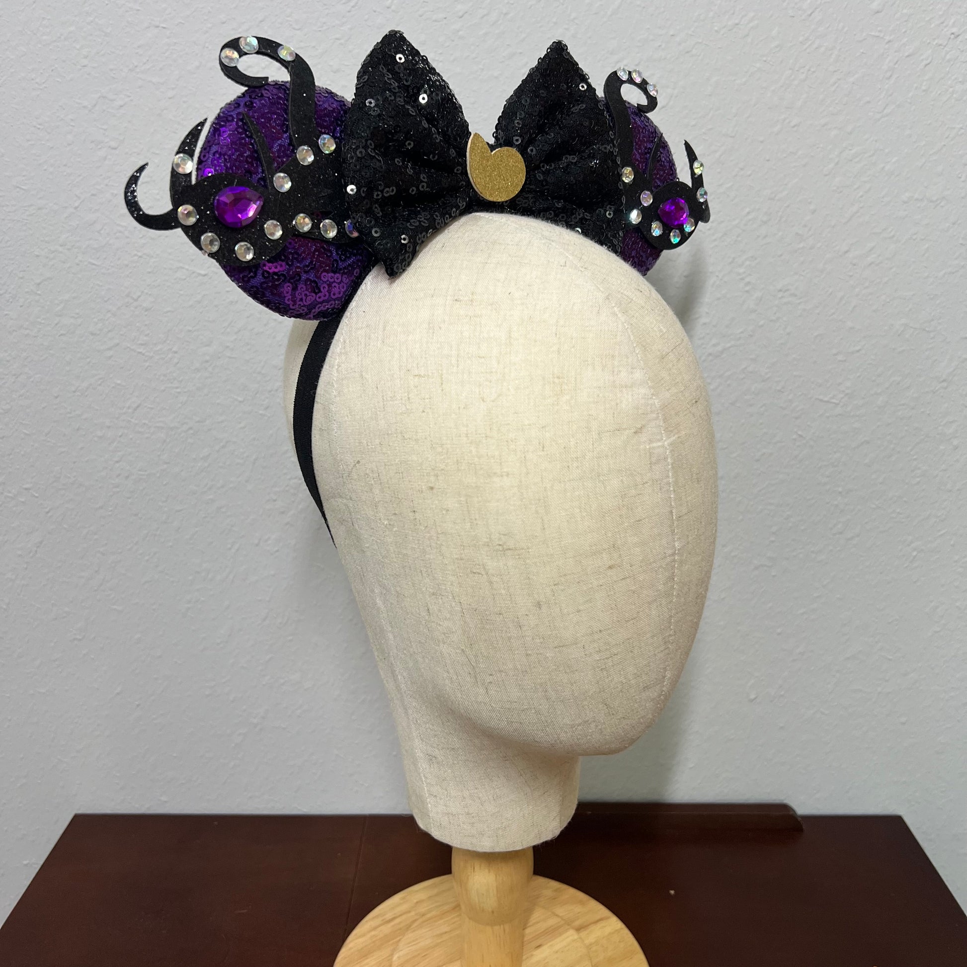 Black and purple mouse ears headband on a mannequin head against a plain background