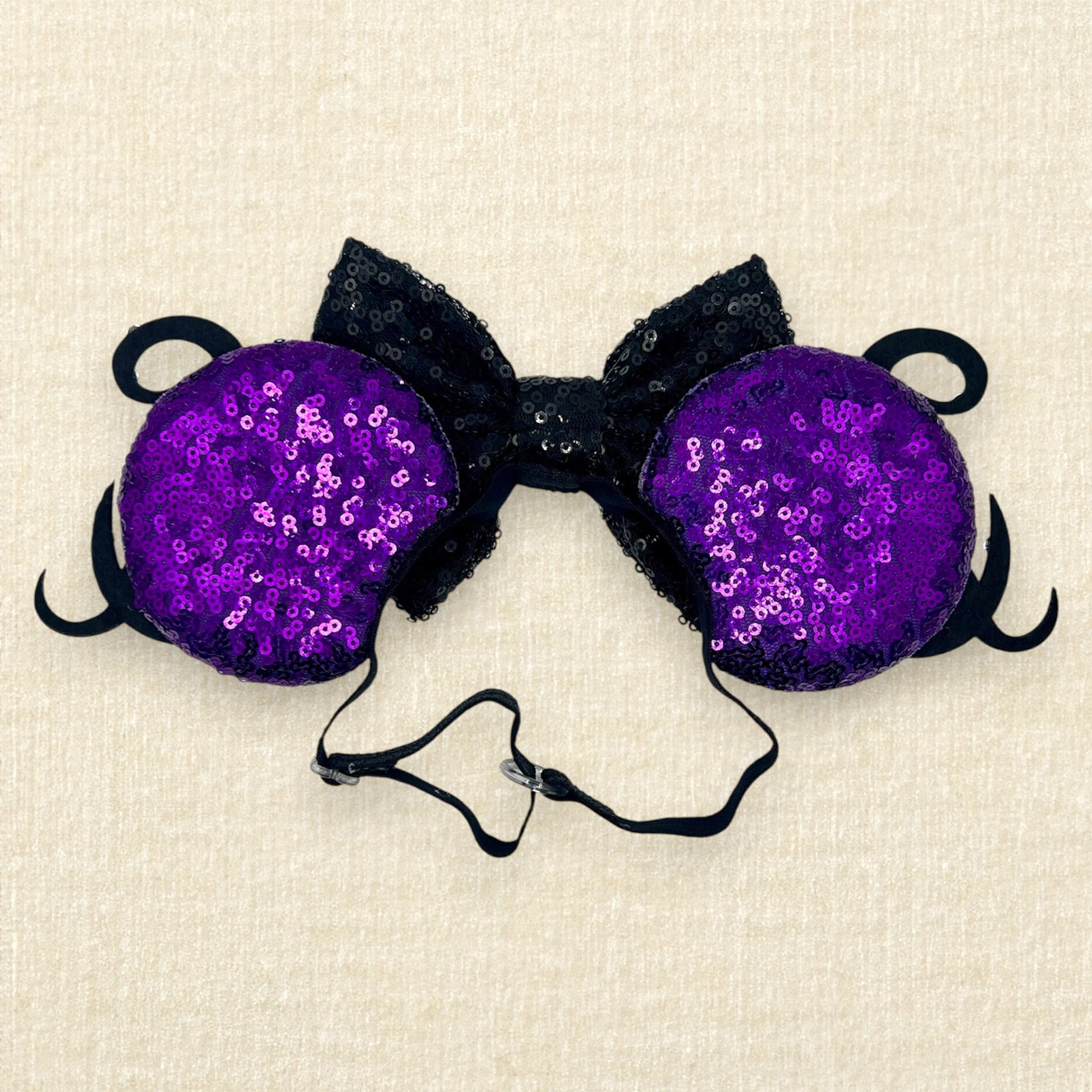 Purple sequin mouse ears with glitter tentacles, rhinestones, and black sequin bow with glitter seashell on an elastic headband (back view)