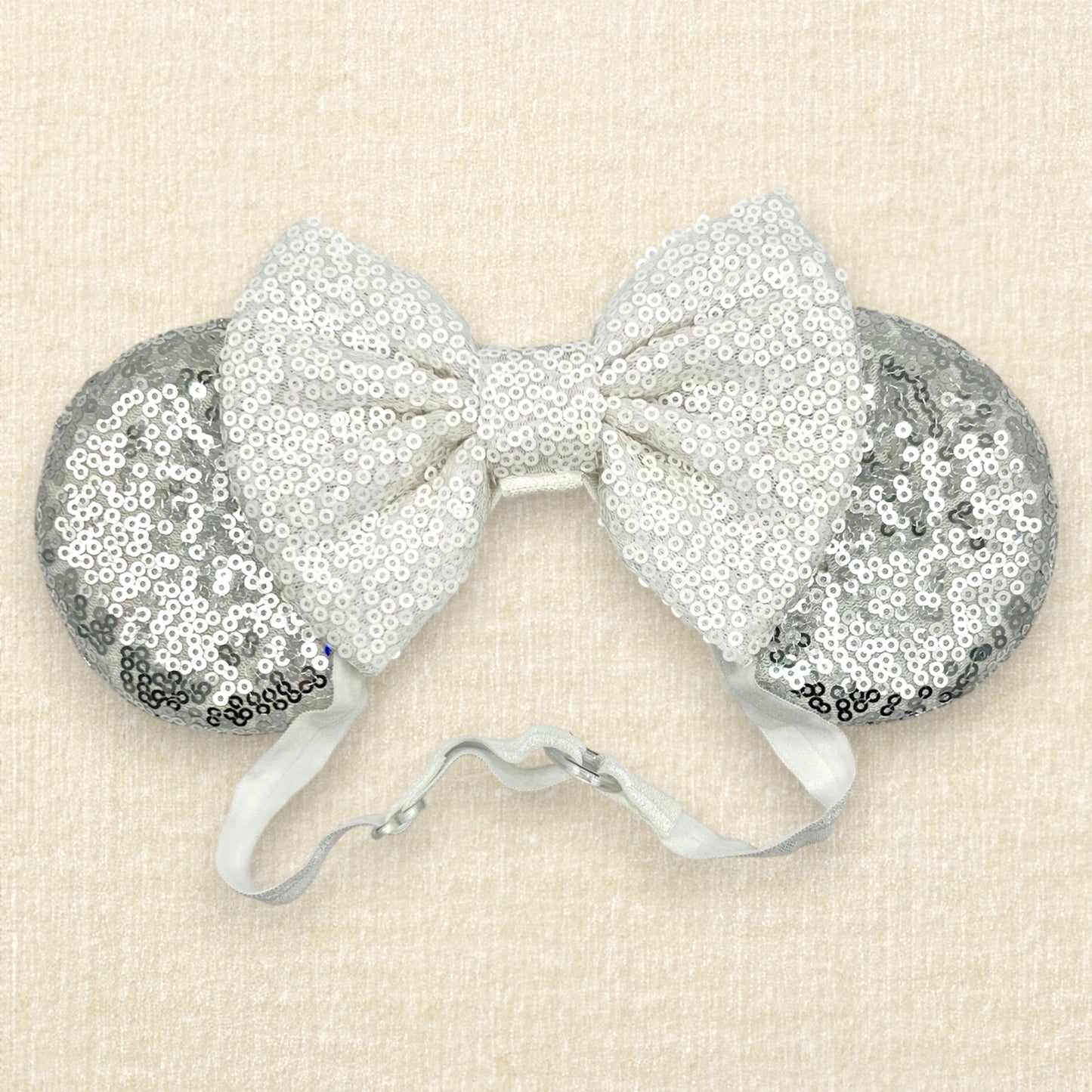 Silver mouse ears with white sequin bow on an elastic headband