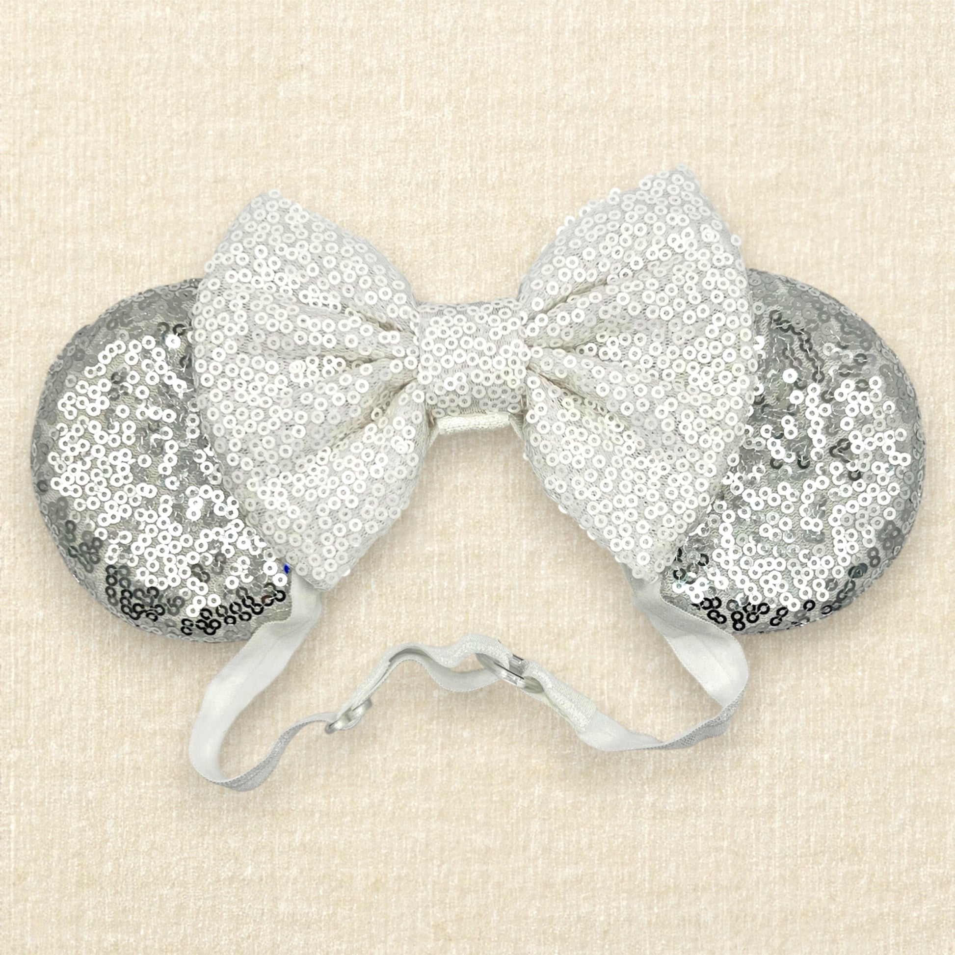 Silver mouse ears with white sequin bow on an elastic headband