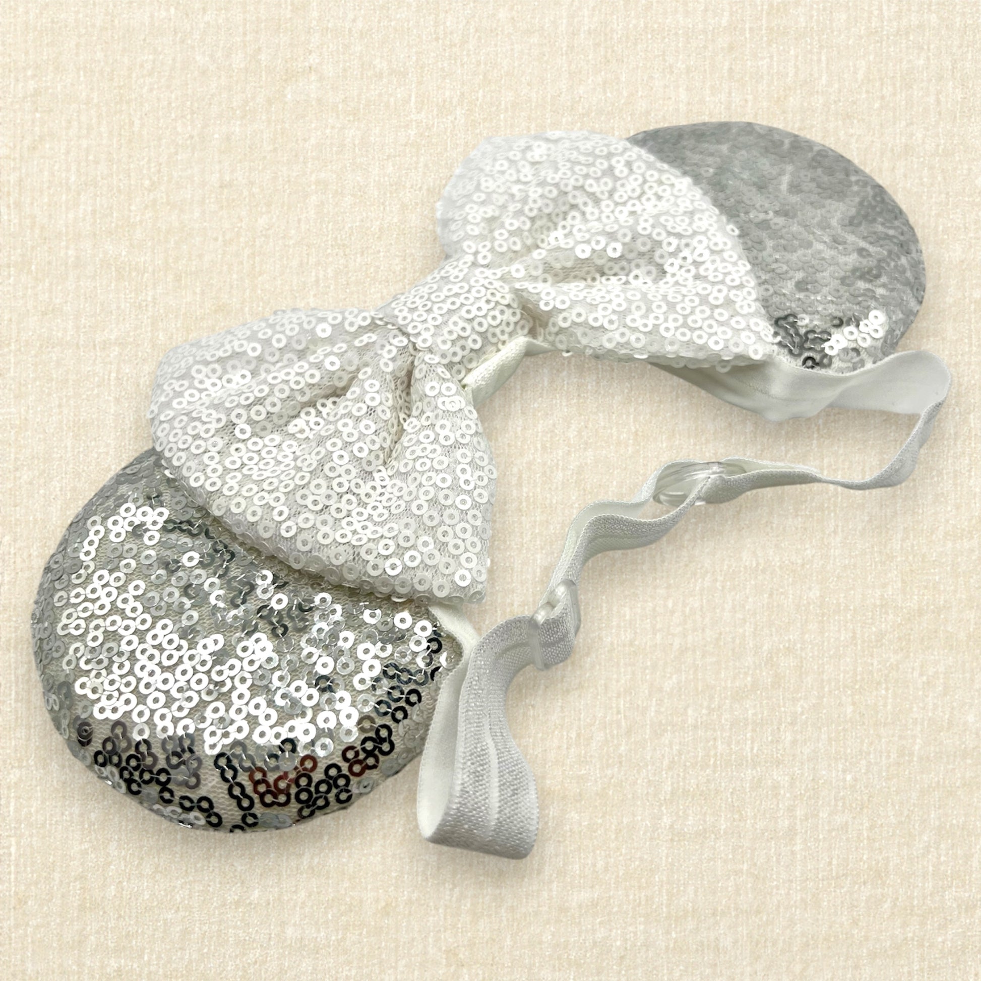 Silver mouse ears with white sequin bow on an elastic headband
