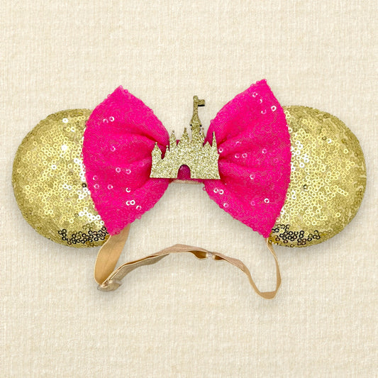 Gold sequin mouse ears with hot pink sequin bow and gold glitter storybook castle on an elastic headband