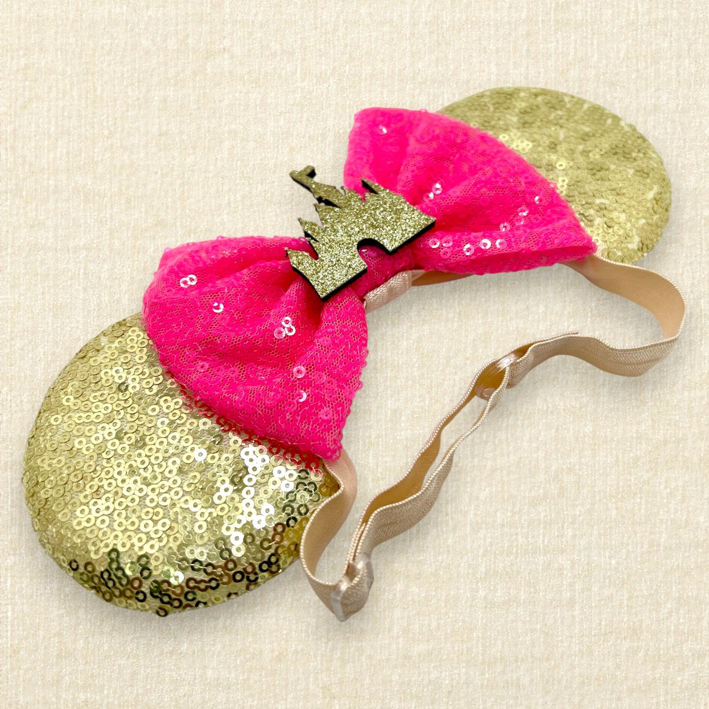 Gold sequin mouse ears with hot pink sequin bow and gold glitter storybook castle on an elastic headband