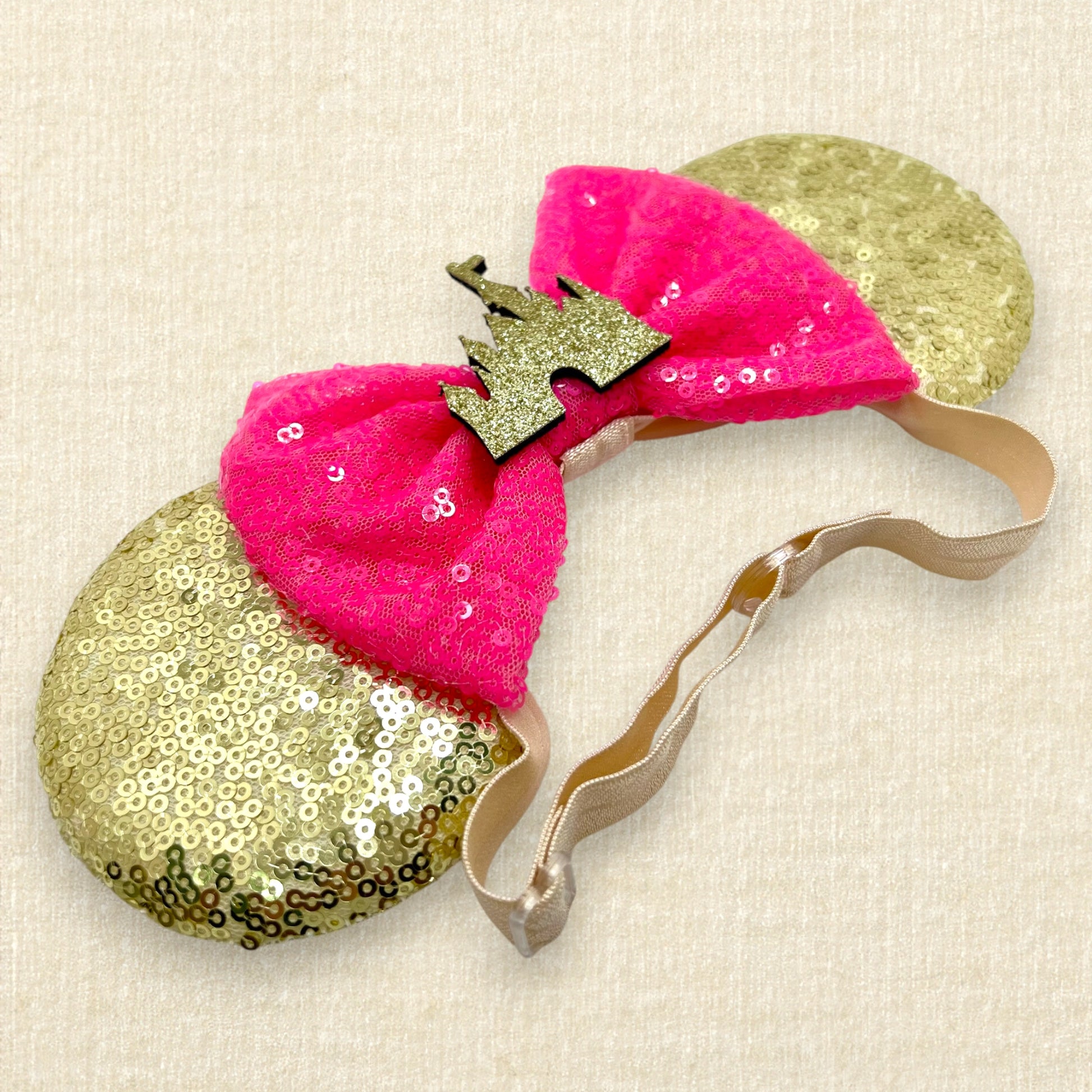 Gold sequin mouse ears with hot pink sequin bow and gold glitter storybook castle on an elastic headband