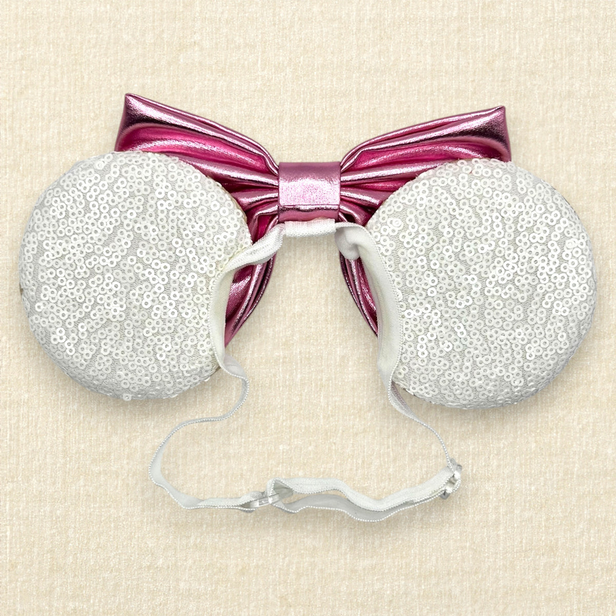 A festive pair of Christmas peppermint mouse ears with white sequin ears, pink glitter candy cane swirls, and a metallic pink bow on an elastic headband (back view)
