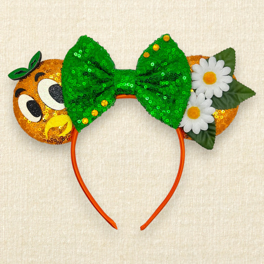 Orange sequin mouse ears with glitter bird details, white fabric daisies, and green sequin bow