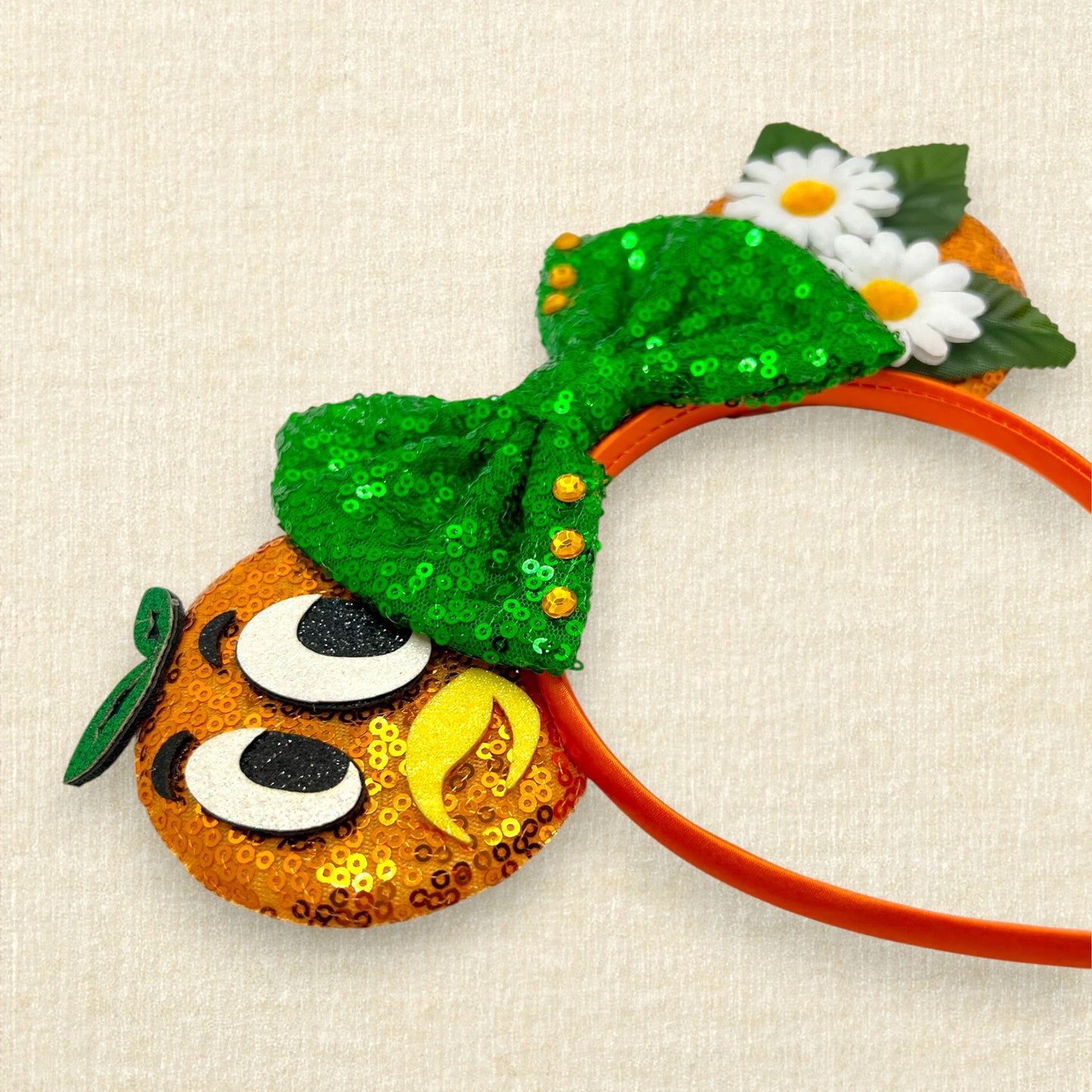 Orange sequin mouse ears with glitter bird details, white fabric daisies, and green sequin bow