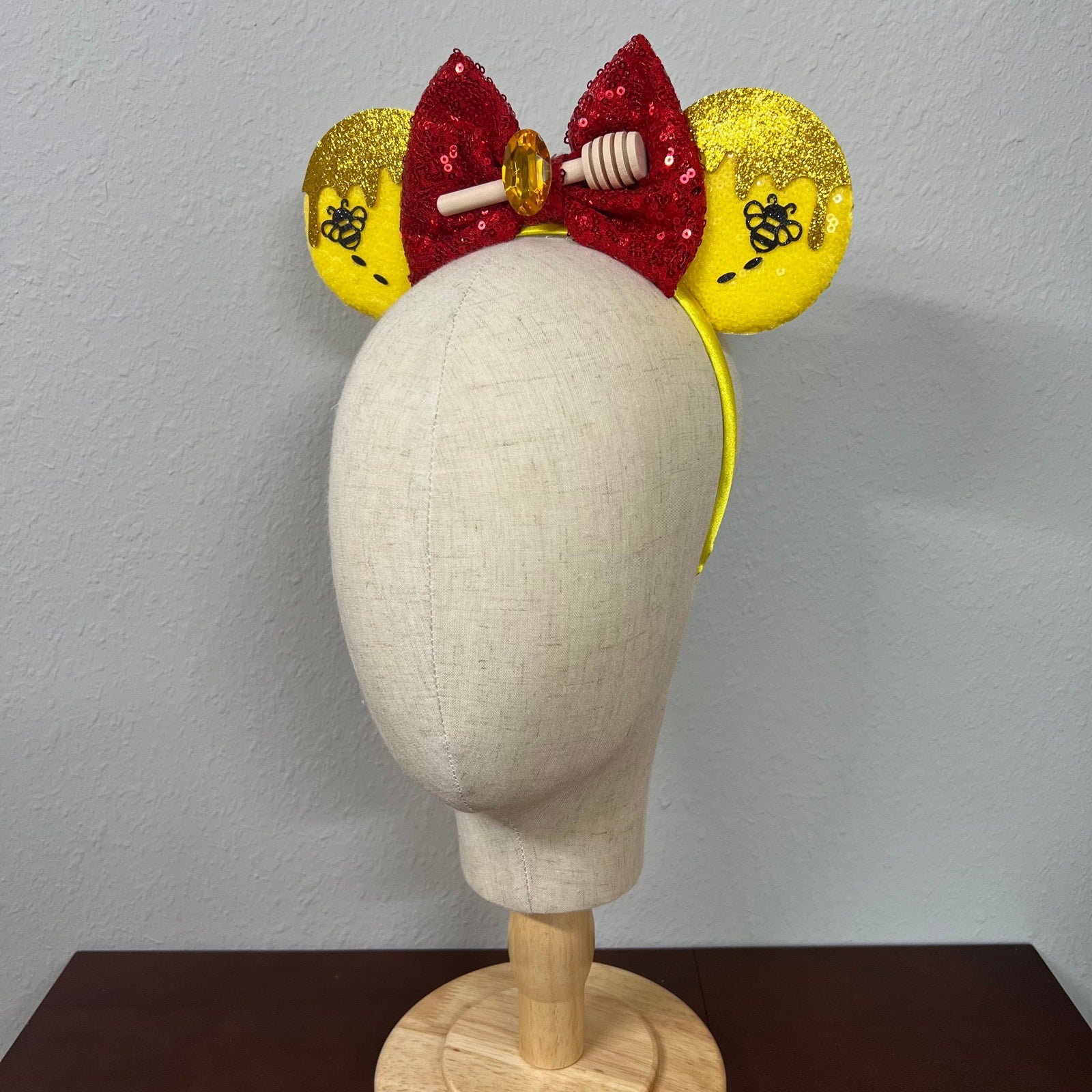 Yellow mouse ears with a red bow on a mannequin head against a gray background