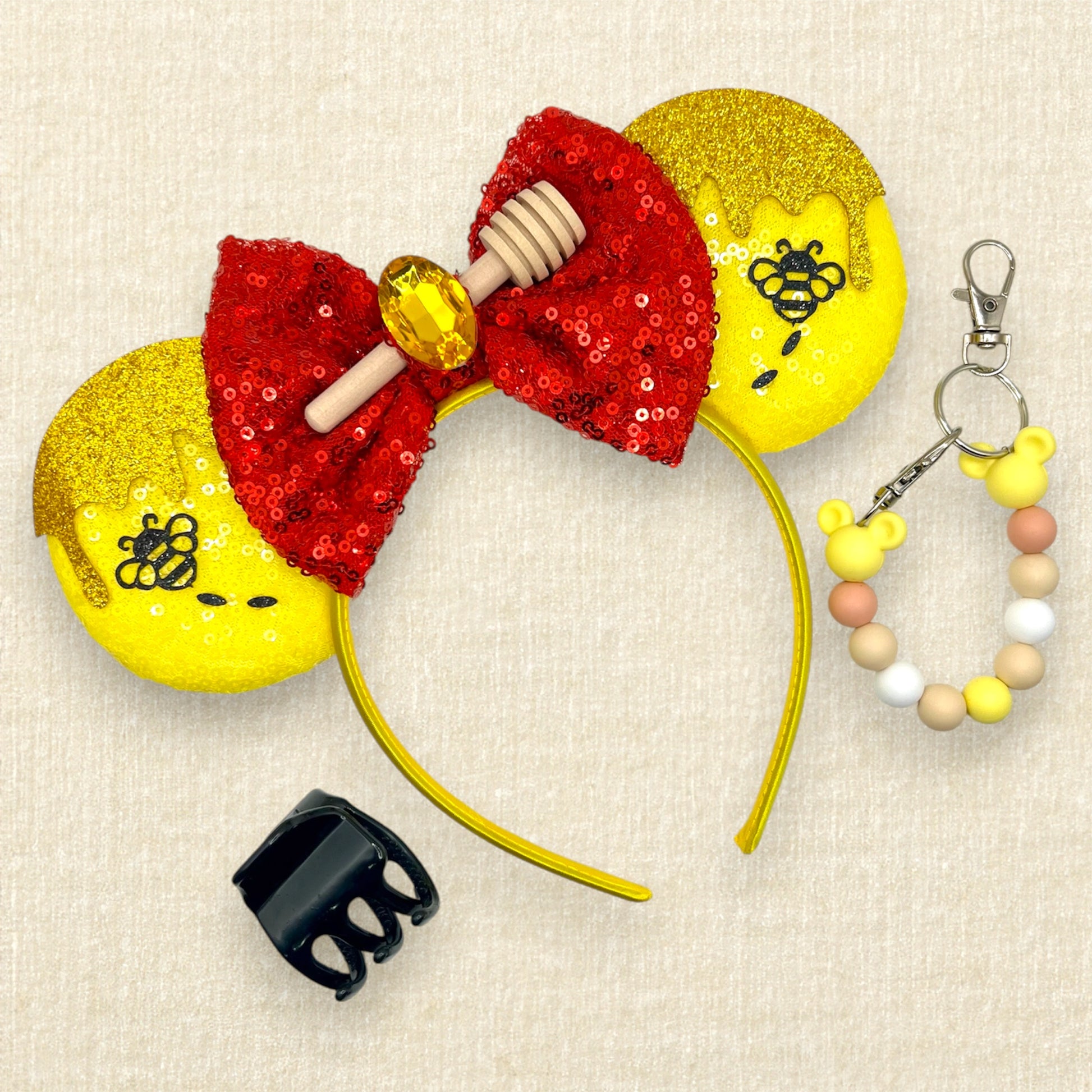 Yellow sequin mouse ears with gold glitter honey and black bumblebee accents, and red sequin bow with wooden honey dipper and gold rhinestone; black claw clip; yellow beaded mouse ears holder