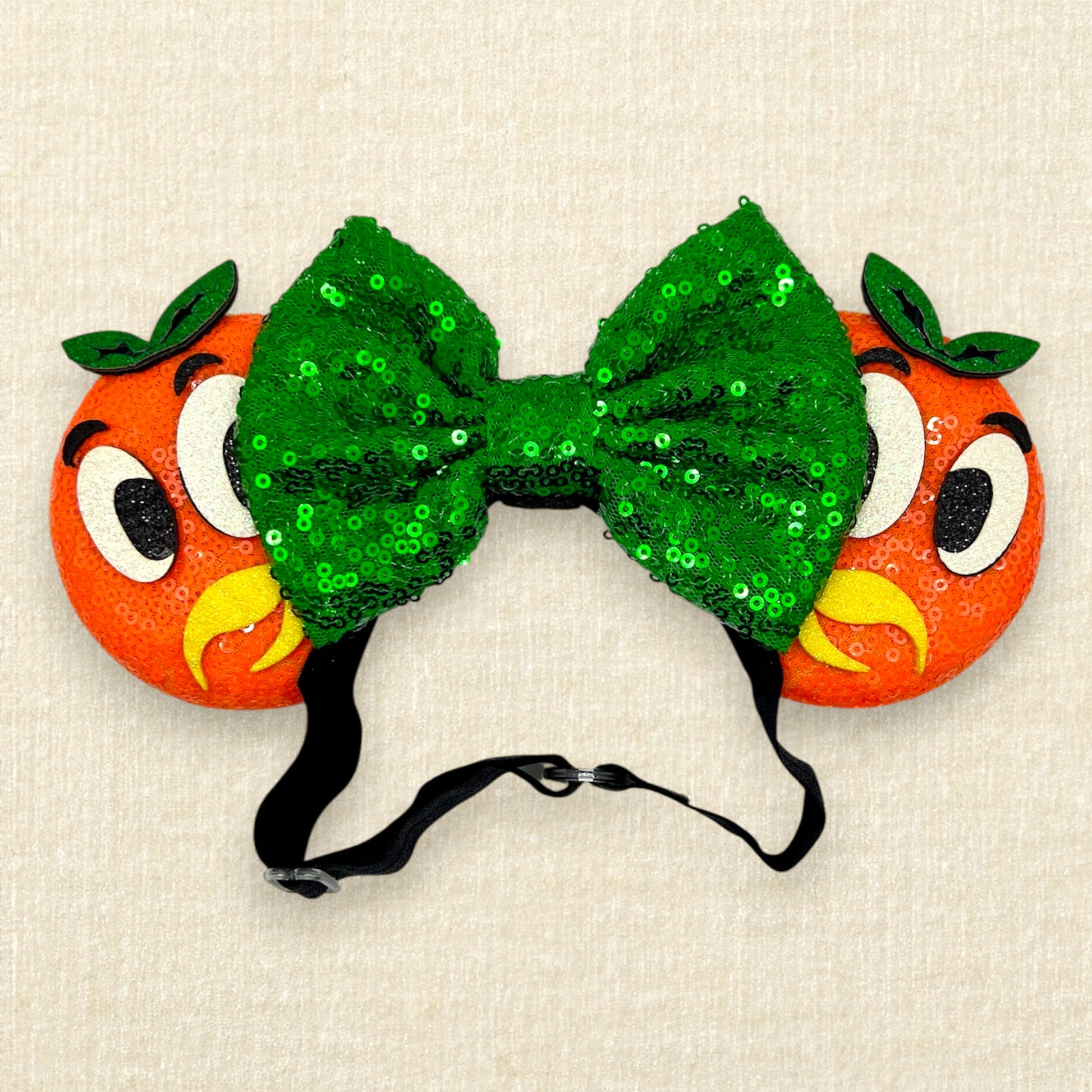 Orange mouse ears on an elastic headband with green sequin bow and glitter bird details