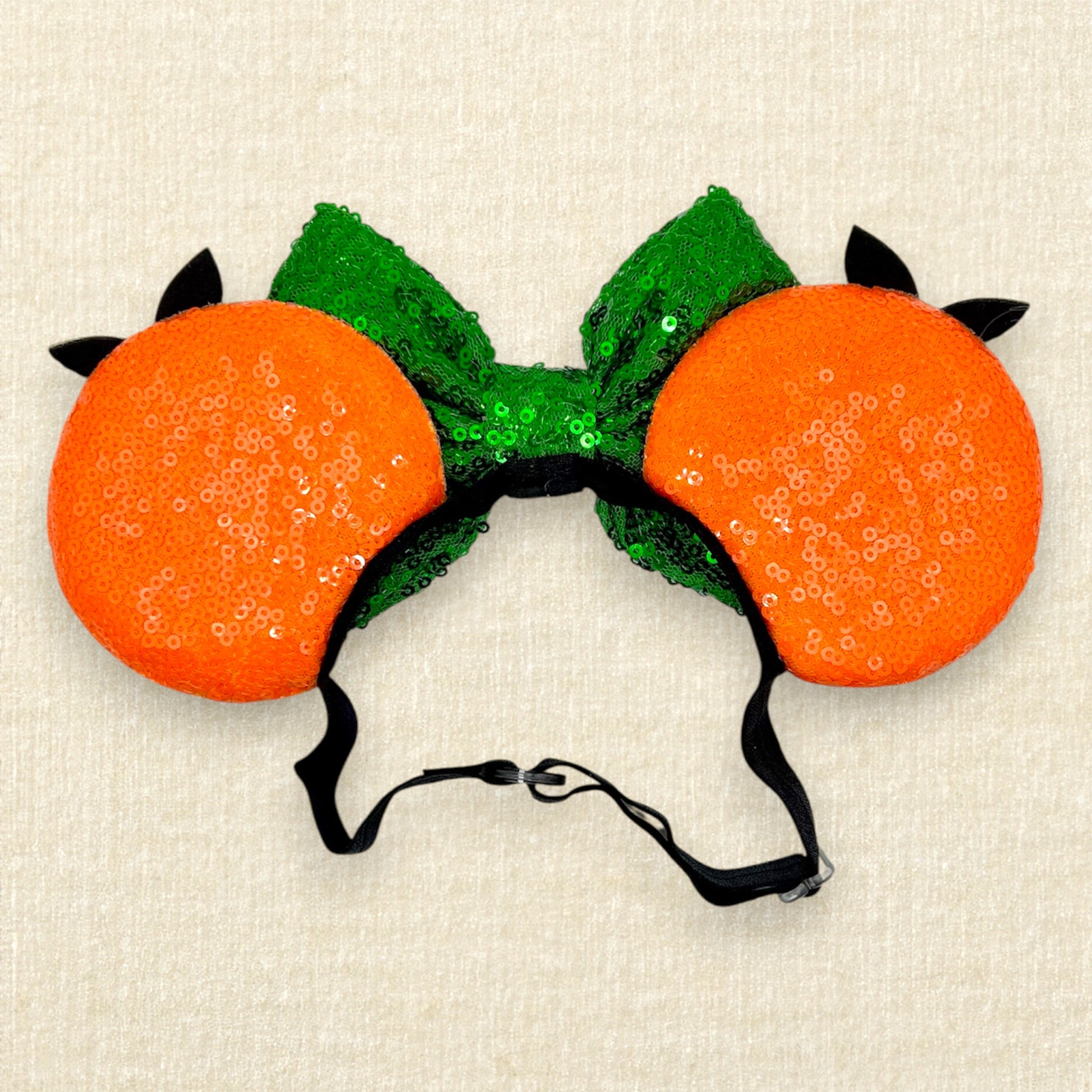Orange mouse ears on an elastic headband with green sequin bow and glitter bird details