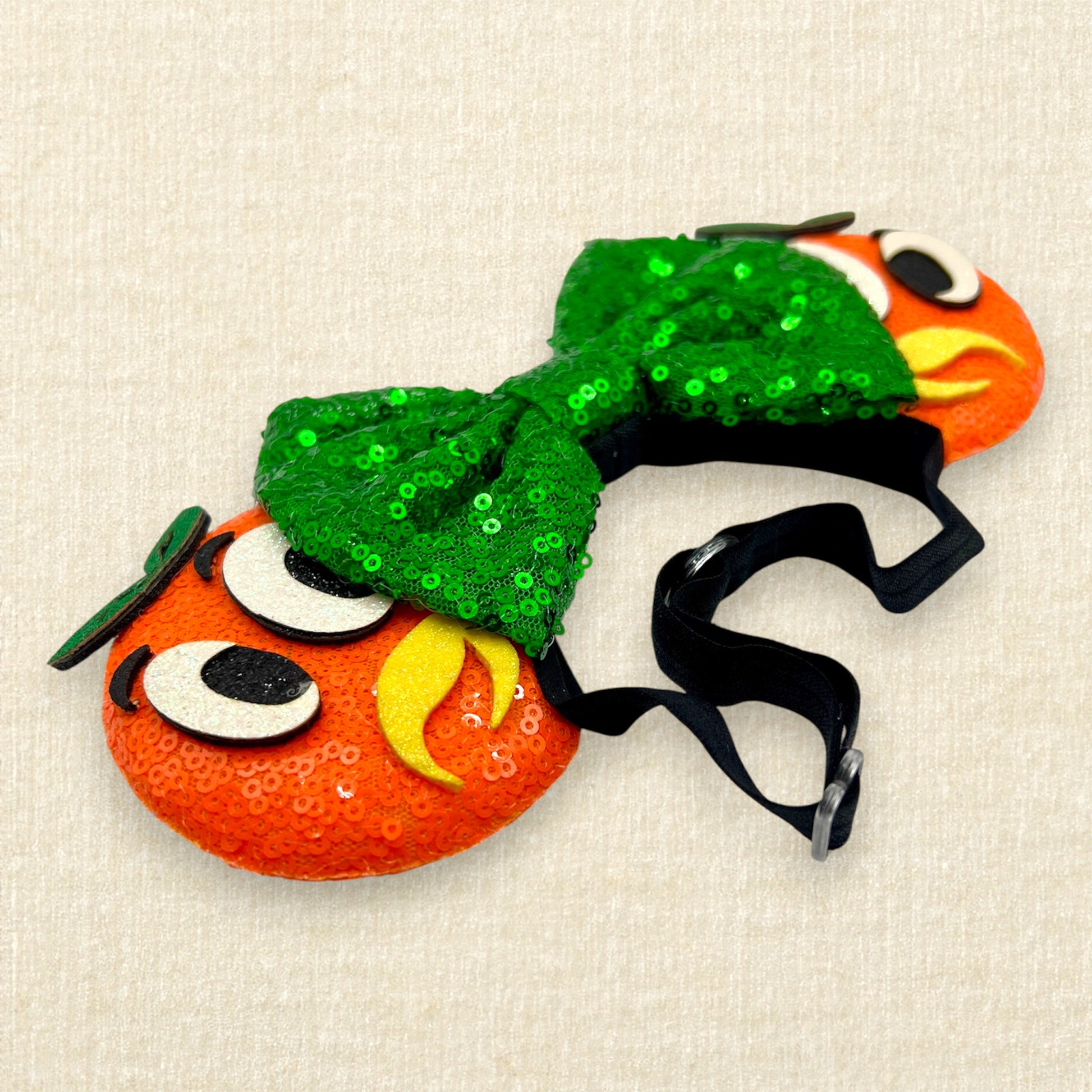 Orange mouse ears on an elastic headband with green sequin bow and glitter bird details