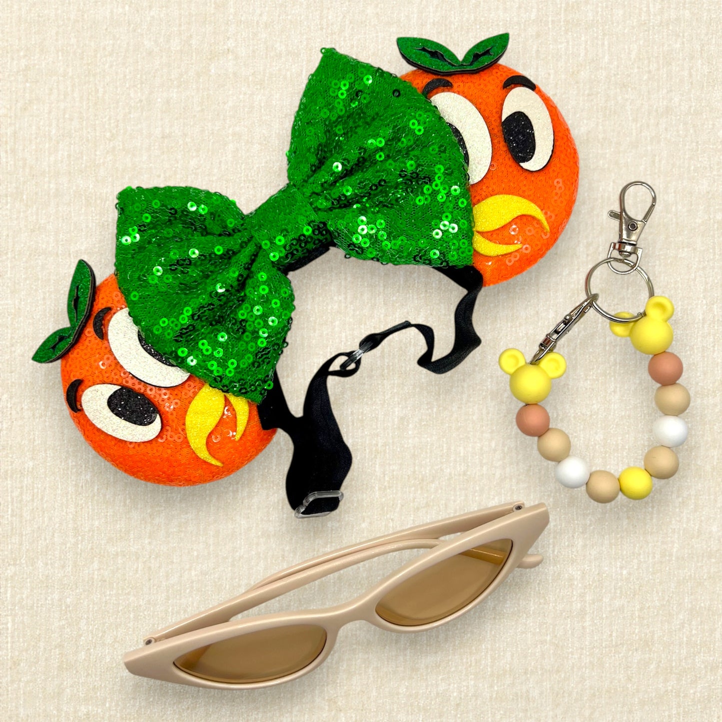 Orange mouse ears on an elastic headband with green sequin bow and glitter bird details; beaded mouse ears holder; cream cat eye sunglasses