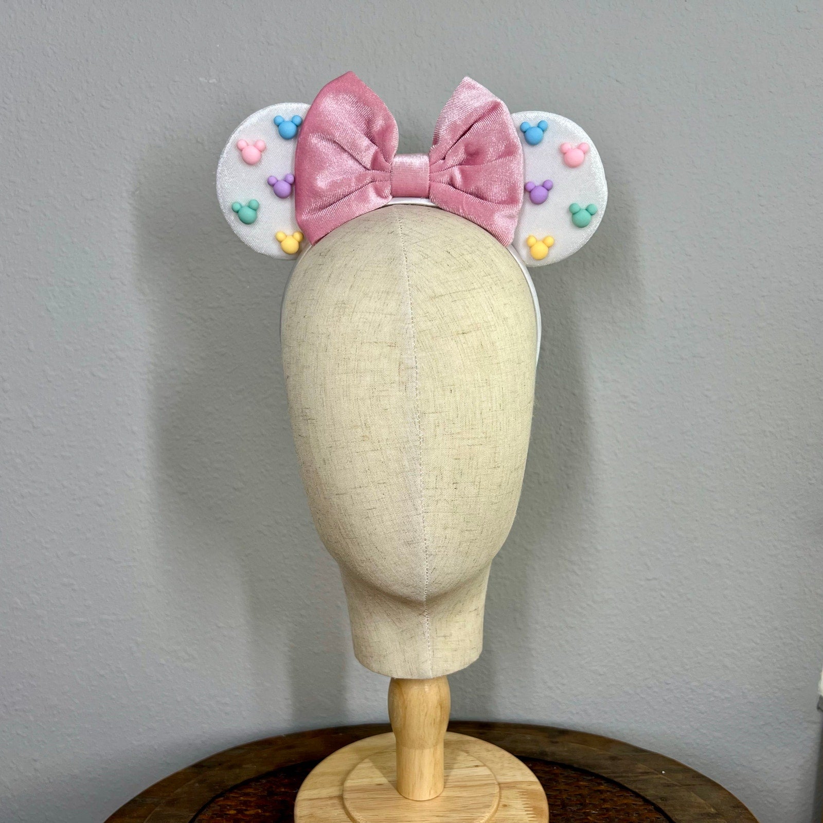 White mouse ears with a pink bow and pastel mouse-shaped pearls on a mannequin