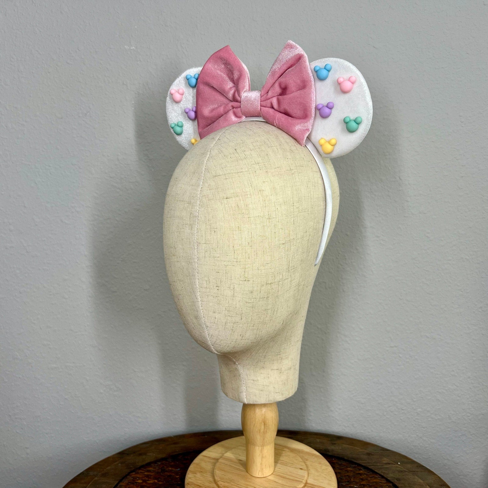 White mouse ears with a pink bow and pastel mouse-shaped pearls on a mannequin