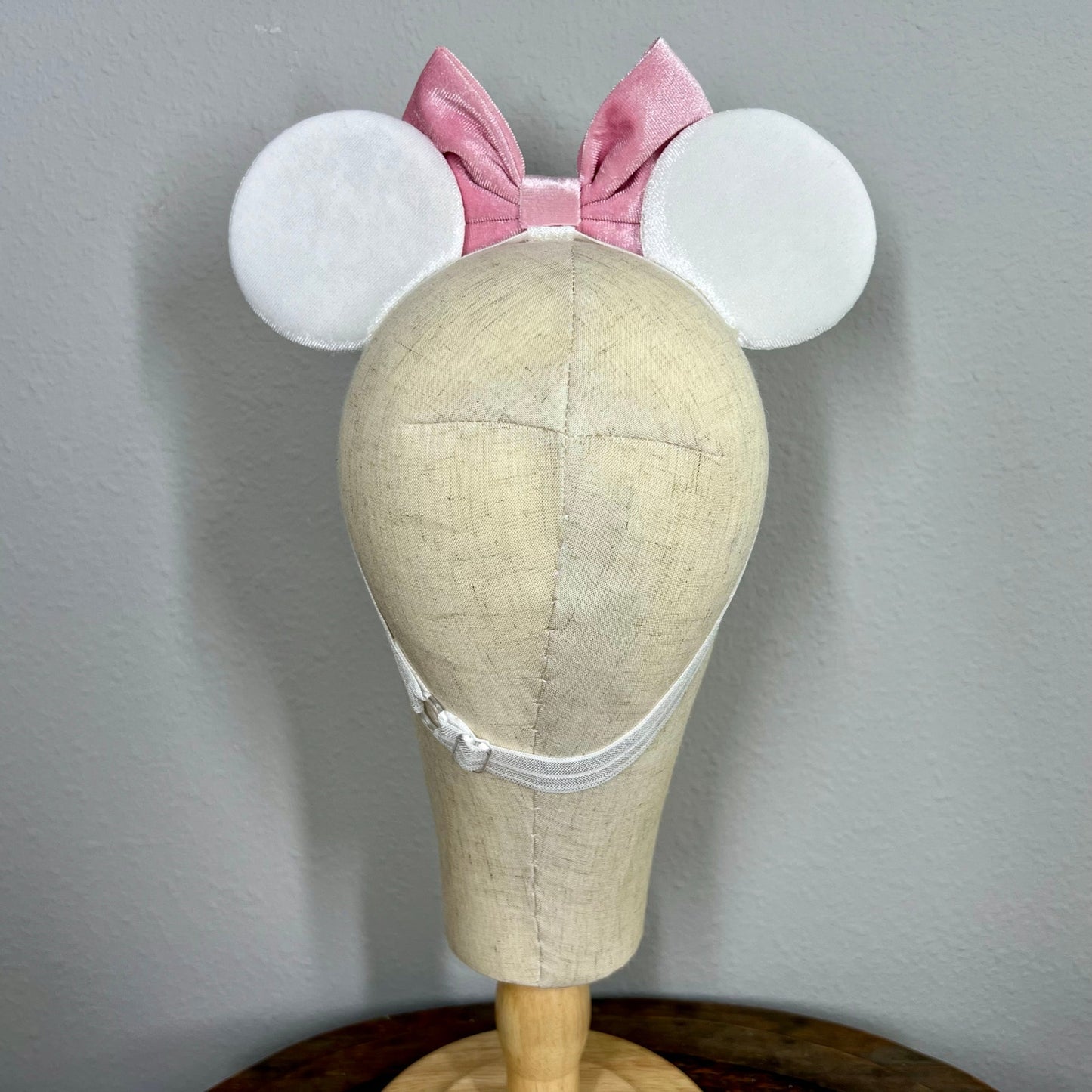 White mouse ears with pastel pink bow and pastel mouse shaped pearls on a mannequin
