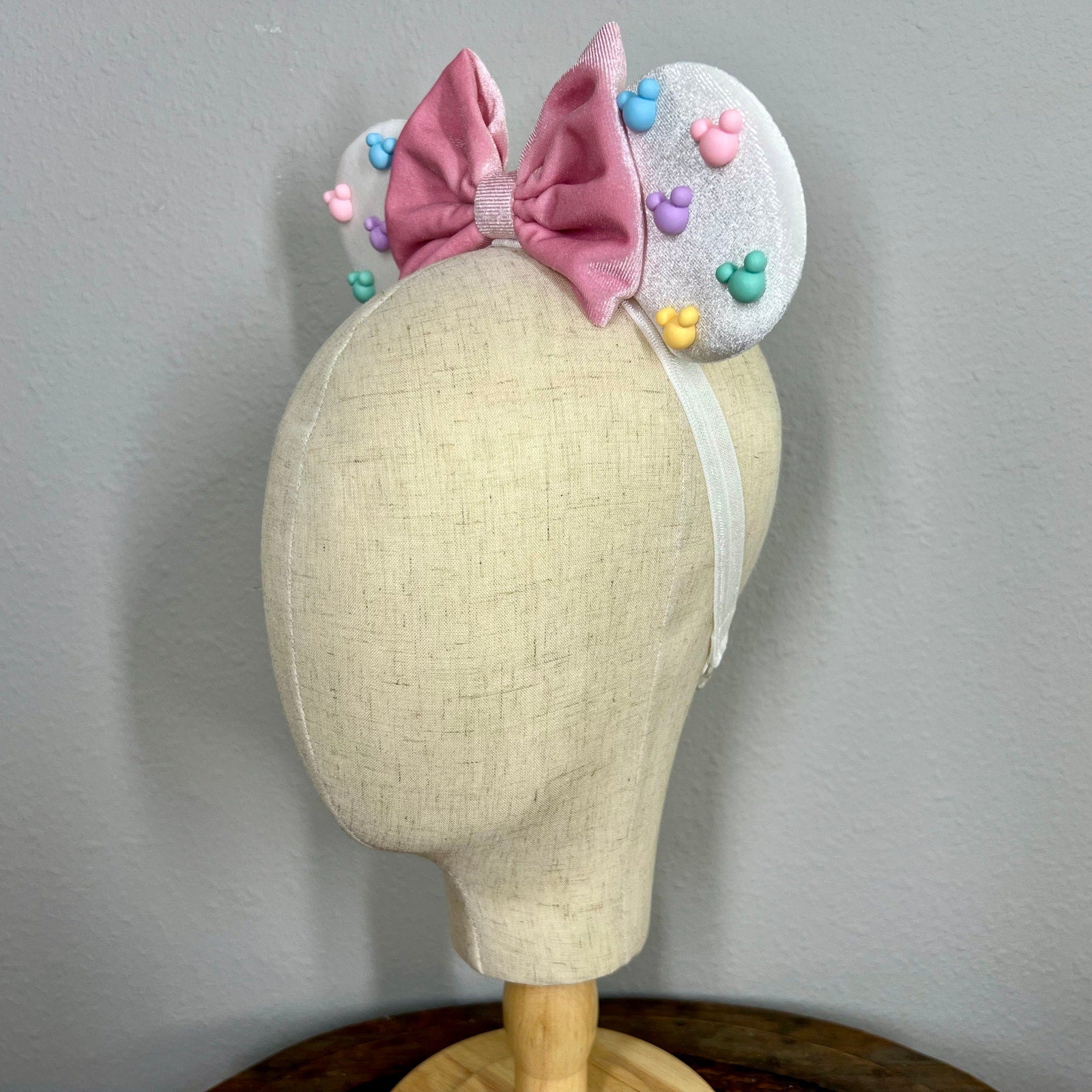 White mouse ears with pastel pink bow and pastel mouse shaped pearls on a mannequin
