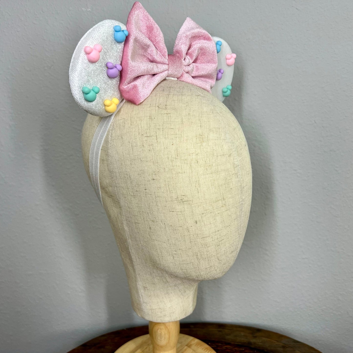 White mouse ears with pastel pink bow and pastel mouse shaped pearls on a mannequin