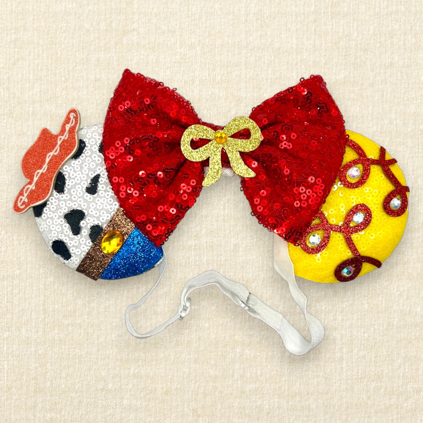Colorful cowboy-themed mouse ears headband with glitter details, rhinestones, and red sequin bow on an elastic headband